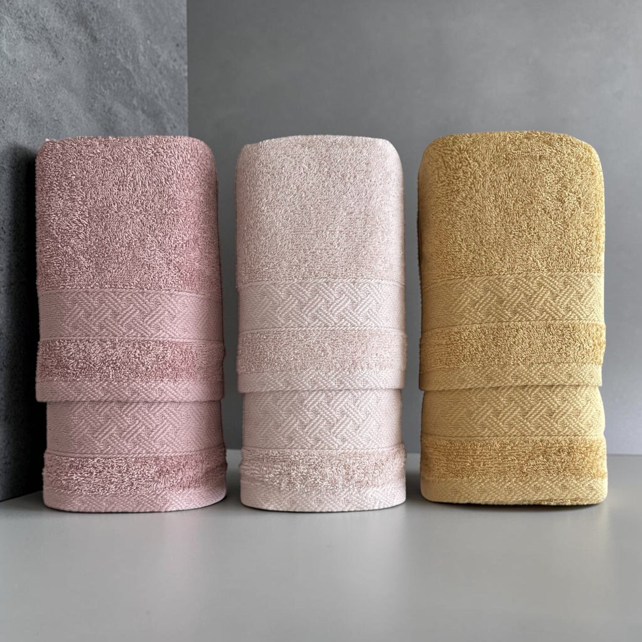Asciugamani viso e ospite Rebecca Home Treccia piegati nei colori rosa antico, cipria e giallo