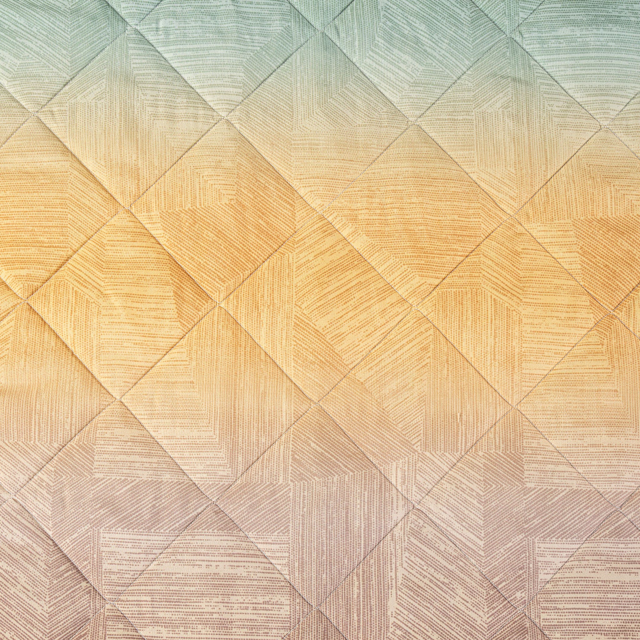 Design sfumato color ambra del copriletto Caleffi Atlantis con trapuntatura geometrica a rombi
