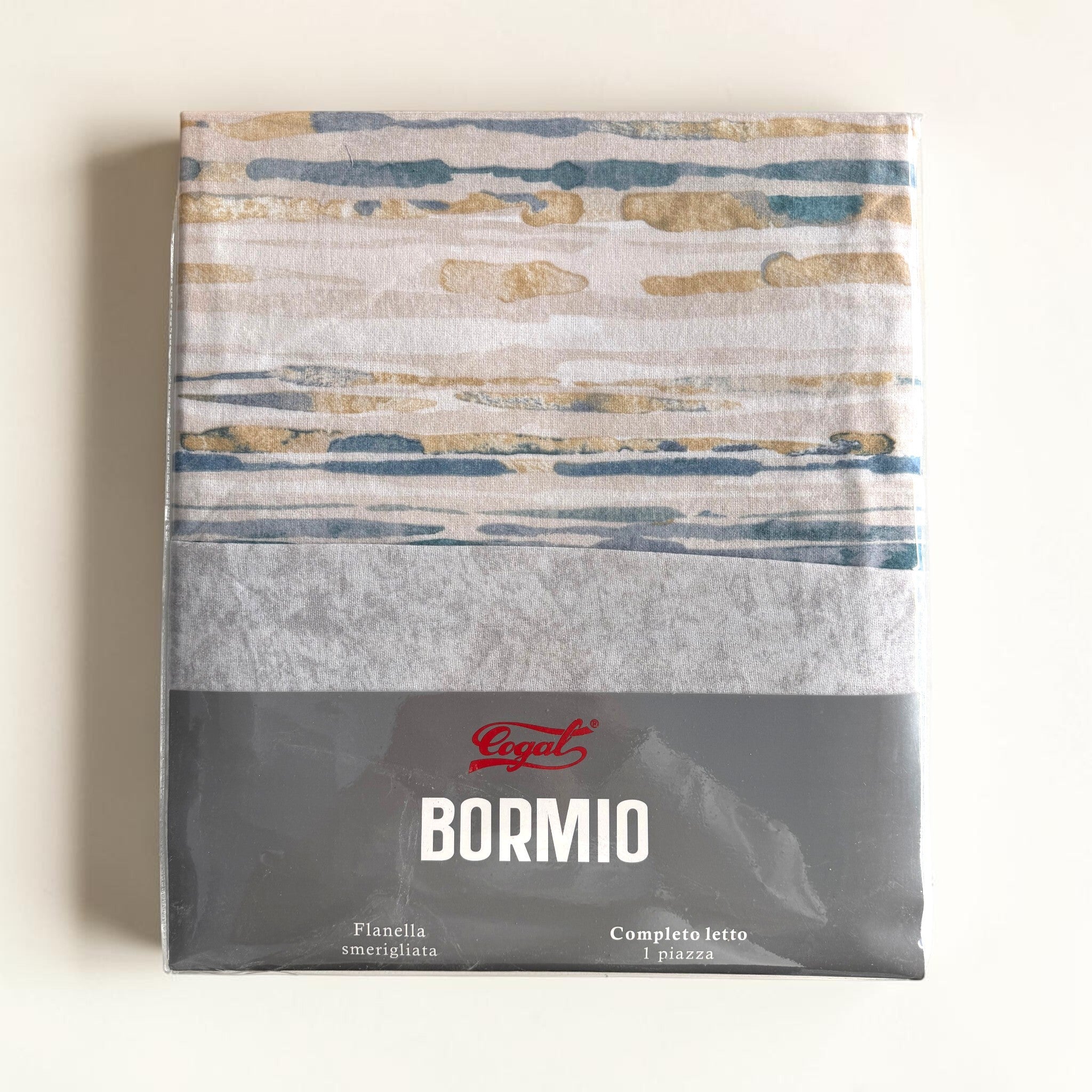 Confezione del completo lenzuola Cogal Bormio 2662 Metal Blue con tessuto a righe colorate e falso unito grigio visibili.