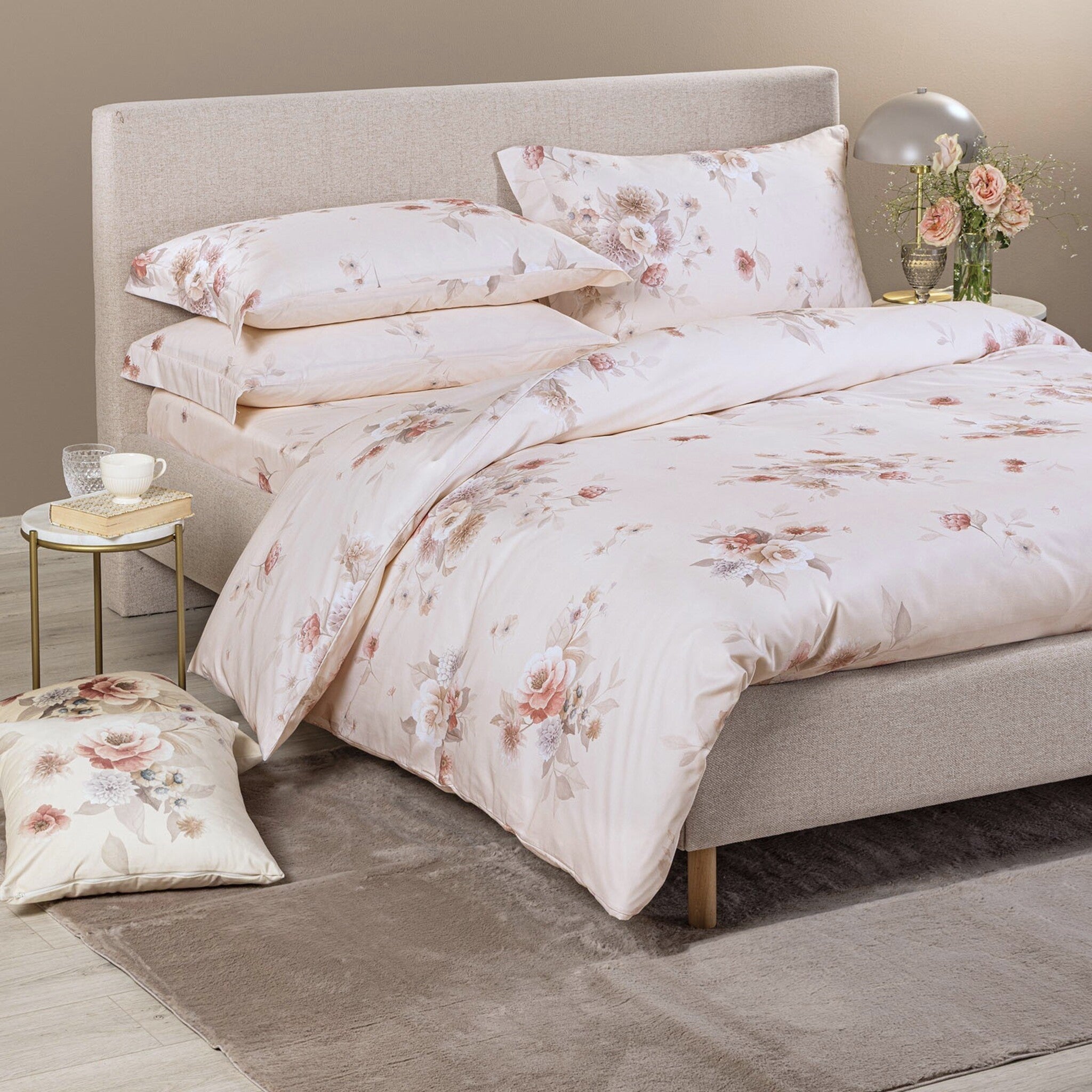 Copripiumino matrimoniale Caleffi Villa D’Este su letto imbottito beige, con bouquet floreali rosa e avorio su fondo chiaro.