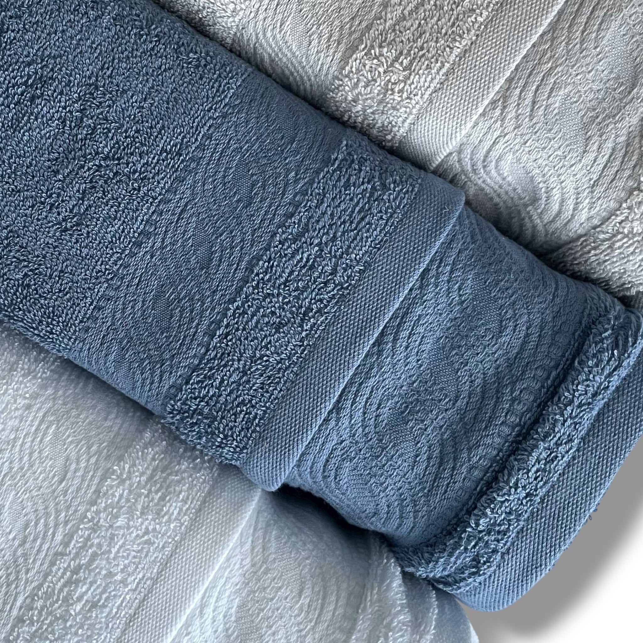 Dettaglio balza jacquard a onde degli asciugamani bianco, indigo e grigio