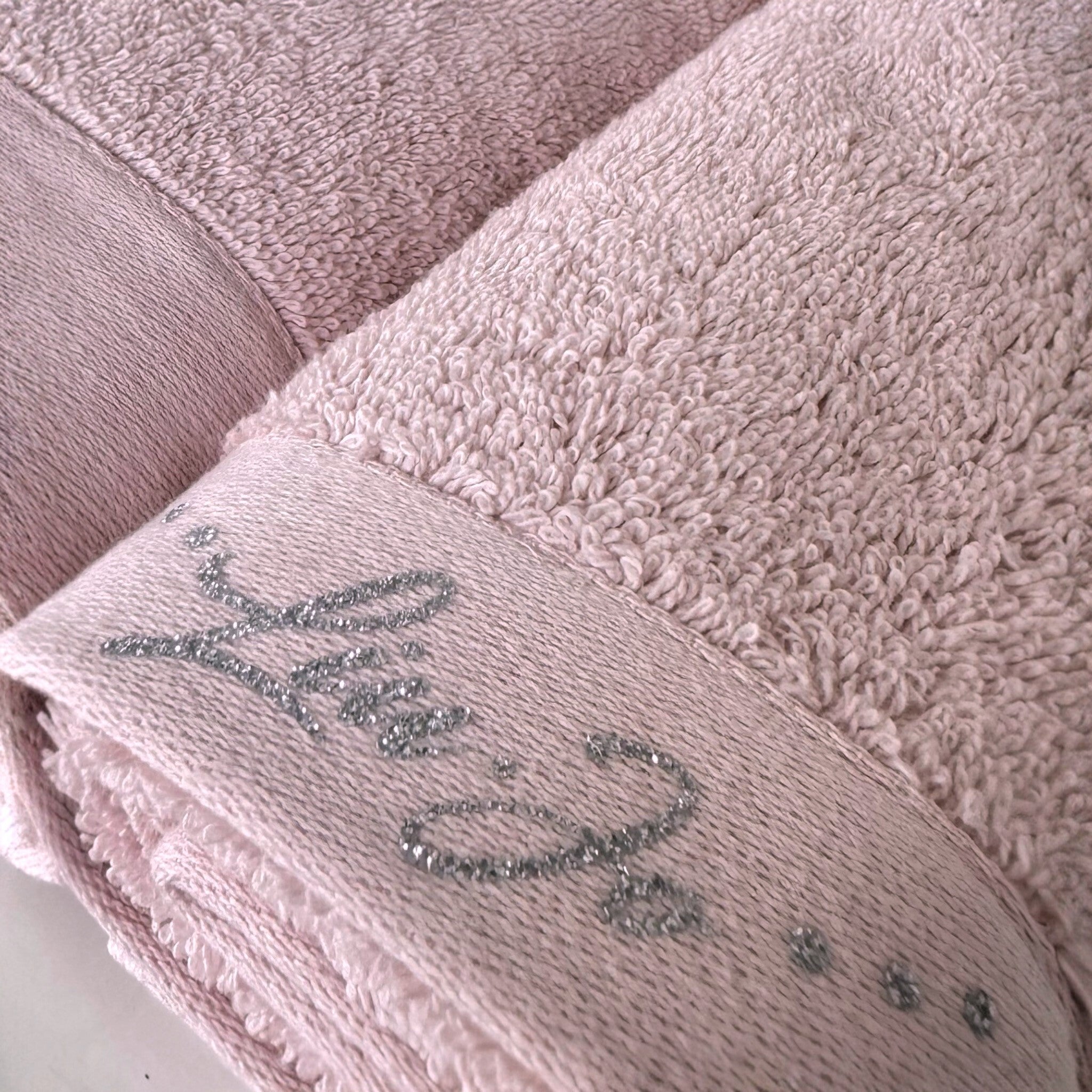Dettaglio della spugna 100% cotone e del logo Liu Jo in lurex argento sull’asciugamano Happy rosa
