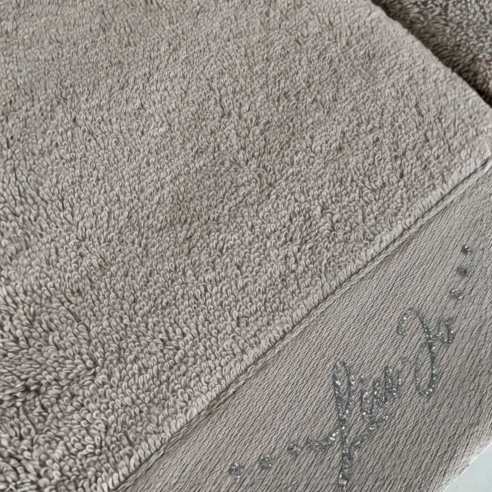 Dettaglio della spugna 100% cotone e del logo Liu Jo in lurex argento sull’asciugamano Happy tortora