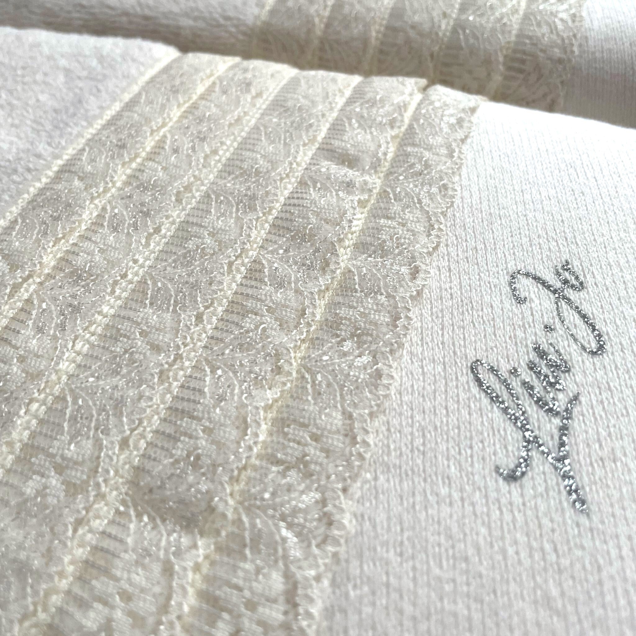 Dettaglio della fascia in pizzo e del logo Liu Jo in lurex sull’asciugamano viso Paradiso Avorio