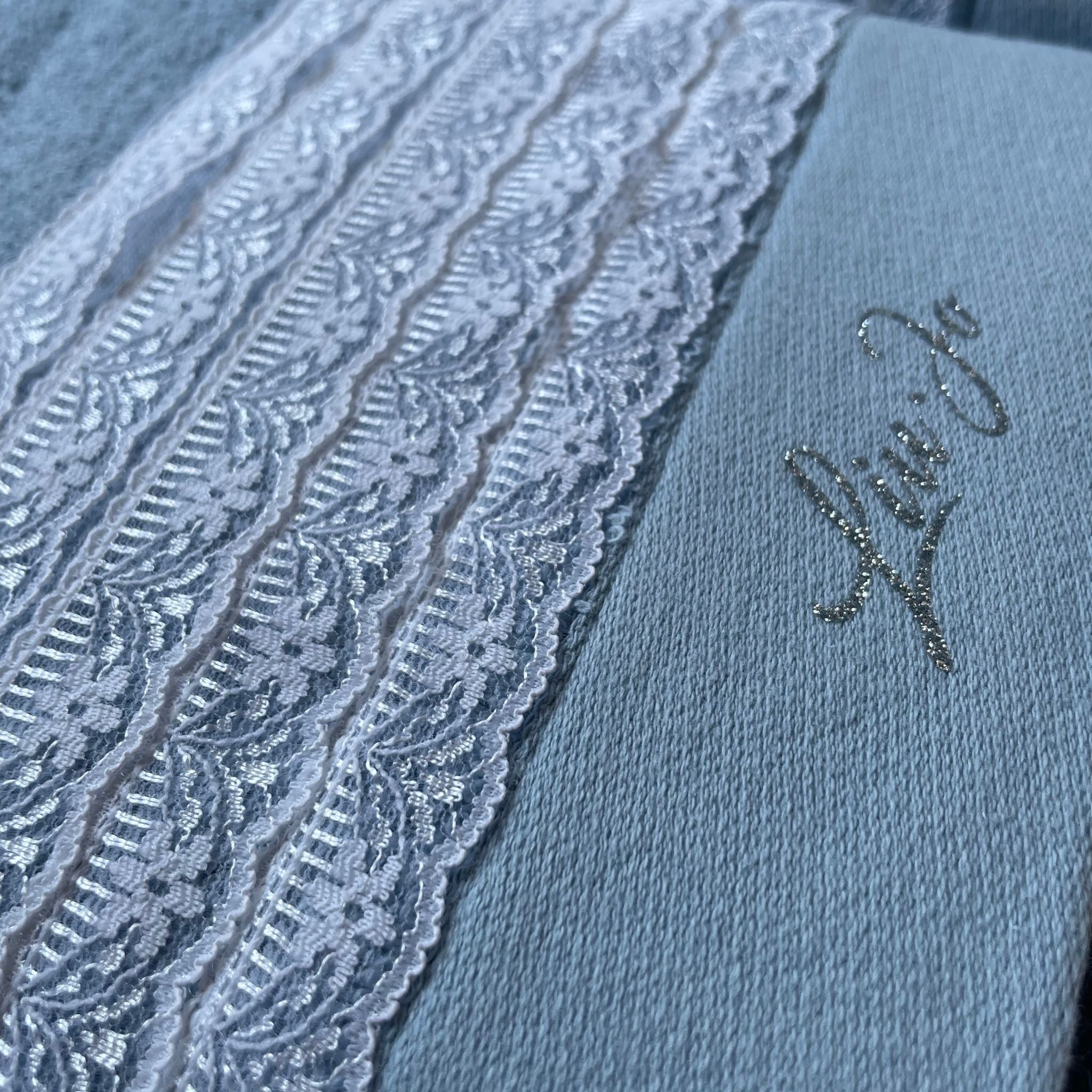 Dettaglio della fascia in pizzo e del logo Liu Jo in lurex sull’asciugamano viso Paradiso Zucchero