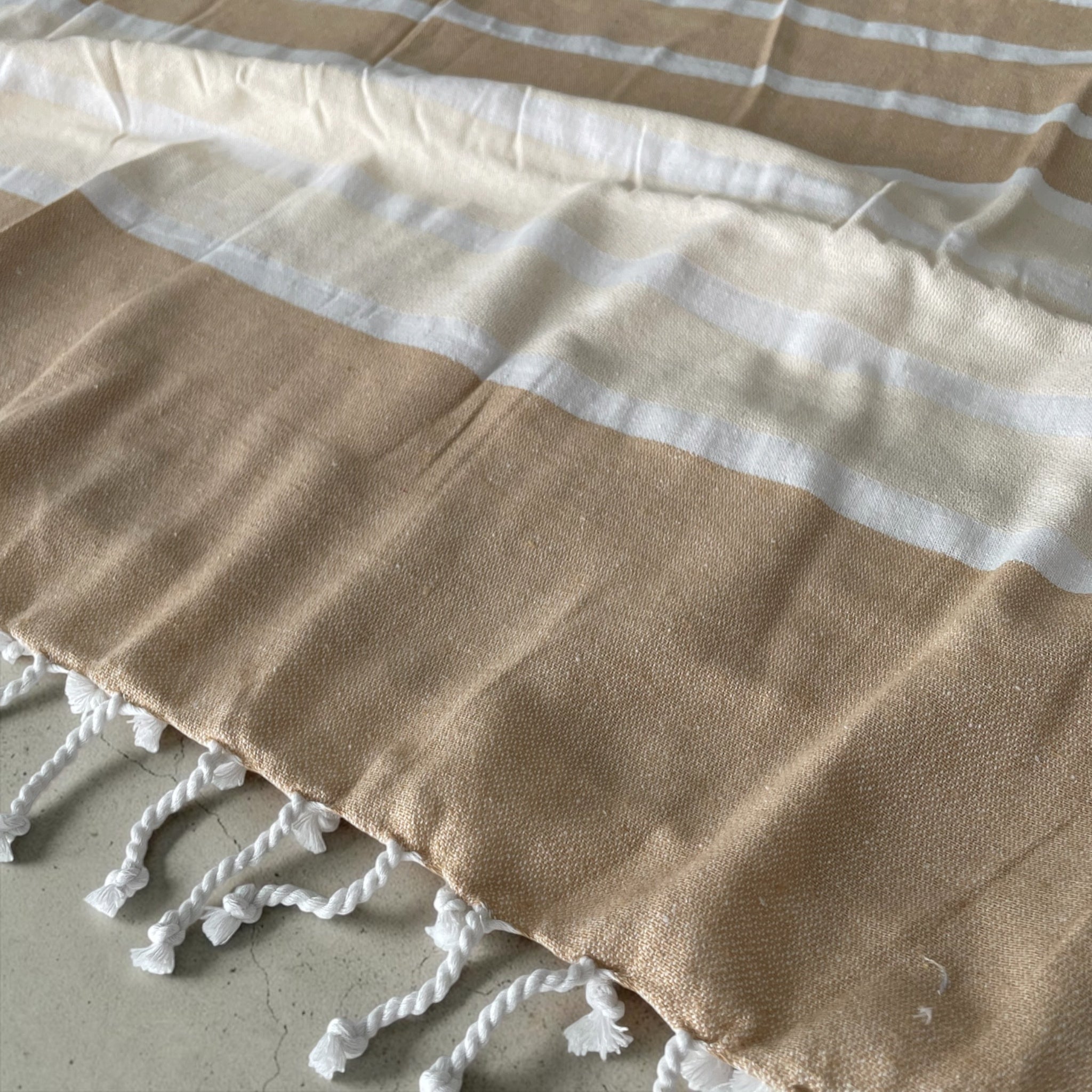 Dettaglio trama in cotone e frange intrecciate del telo mare fouta Curacao Cogal beige