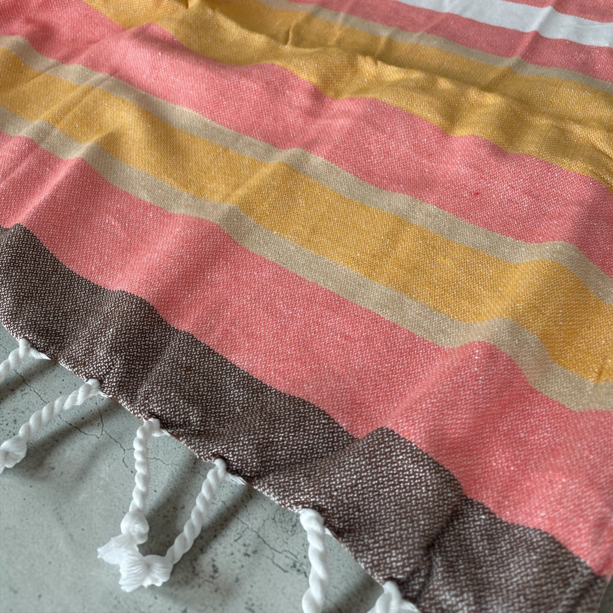 Dettaglio trama in cotone e frange intrecciate del telo mare fouta Curacao Cogal corallo