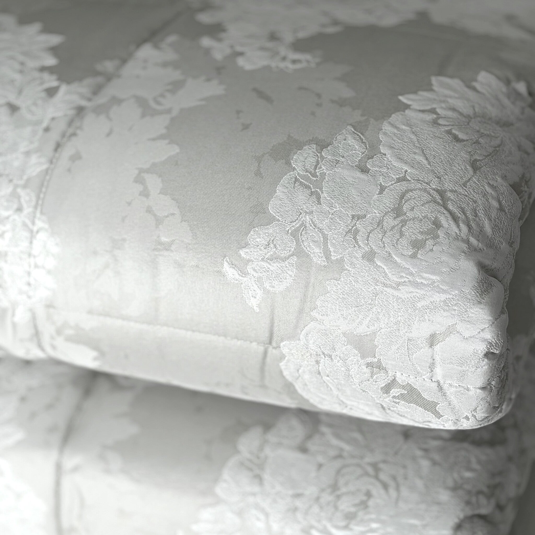 Dettaglio ravvicinato del tessuto floreale in raso jacquard della trapunta Caleffi Gloria colore ghiaccio
