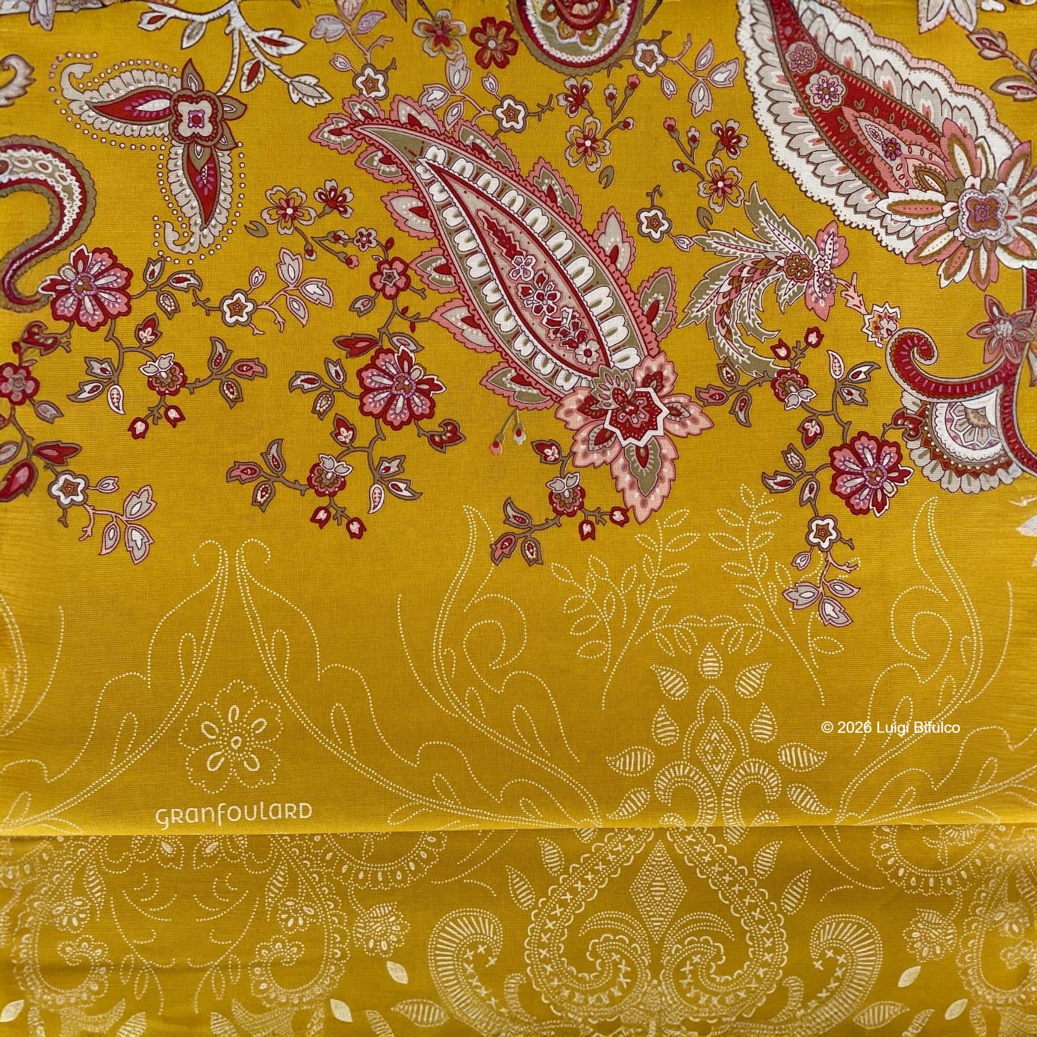 Dettaglio della fantasia Monnalisa Bassetti Granfoulard con elegante motivo paisley floreale su fondo giallo ocra.