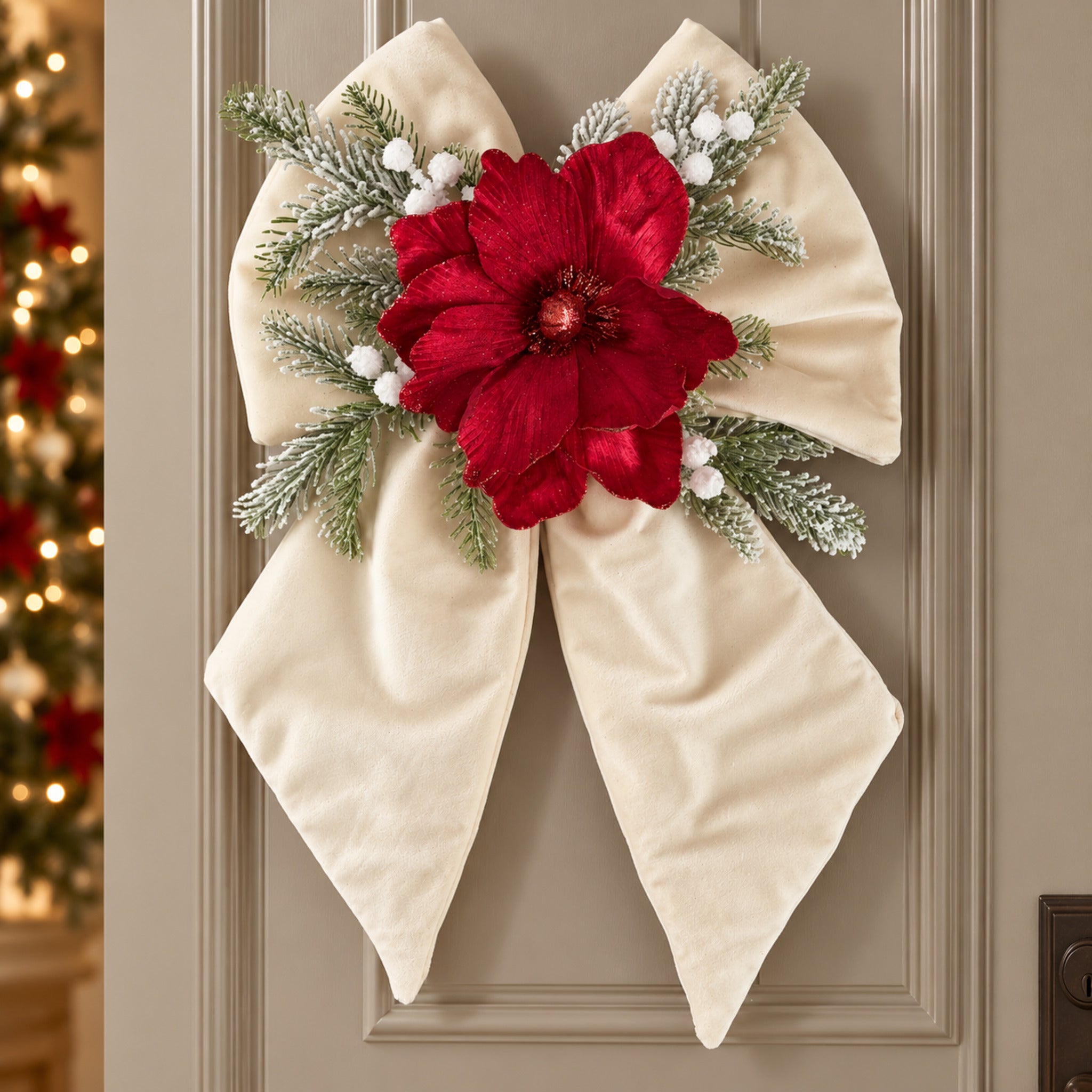 Fiocco natalizio avorio appeso alla porta, con grande fiore rosso, rametti innevati e bacche bianche.