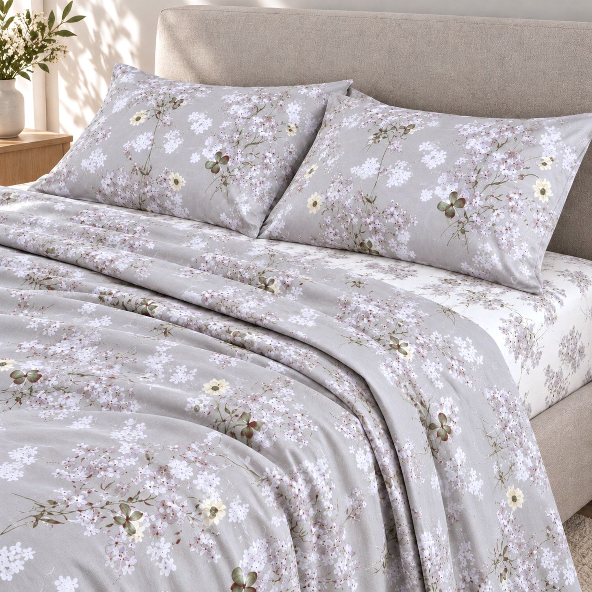 Letto matrimoniale con lenzuola Cogal 2620 Silver Grey a fiori chiari e lenzuolo inferiore in microfantasia su fondo bianco.