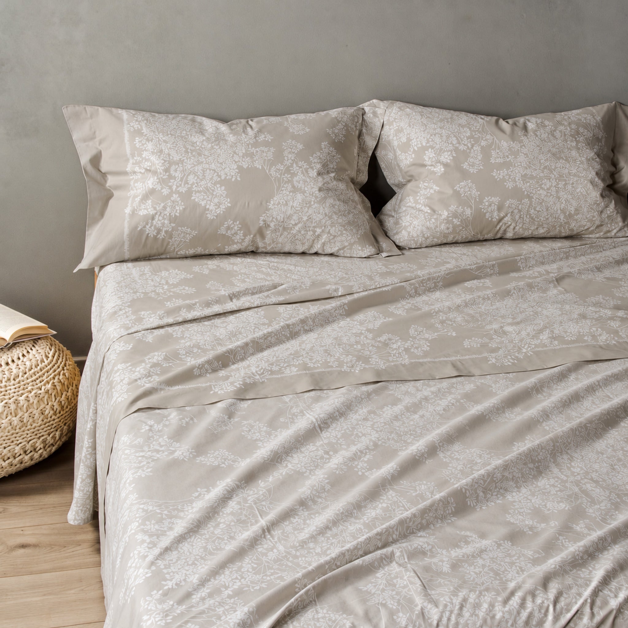 Lenzuola matrimoniali Caleffi Aurora Tortora sul letto, con fantasia di rami fioriti chiari e due federe coordinate.