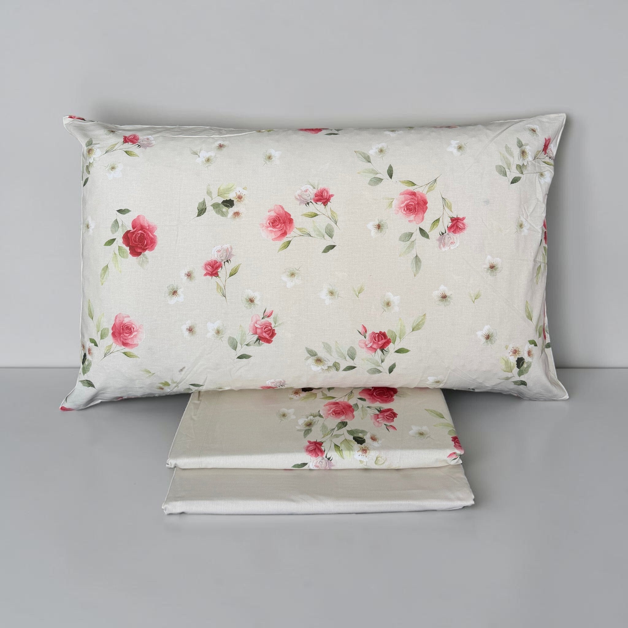 Completo Caleffi Rosier piegato con federa a rose in primo piano e lenzuolo inferiore chiaro in tinta unita