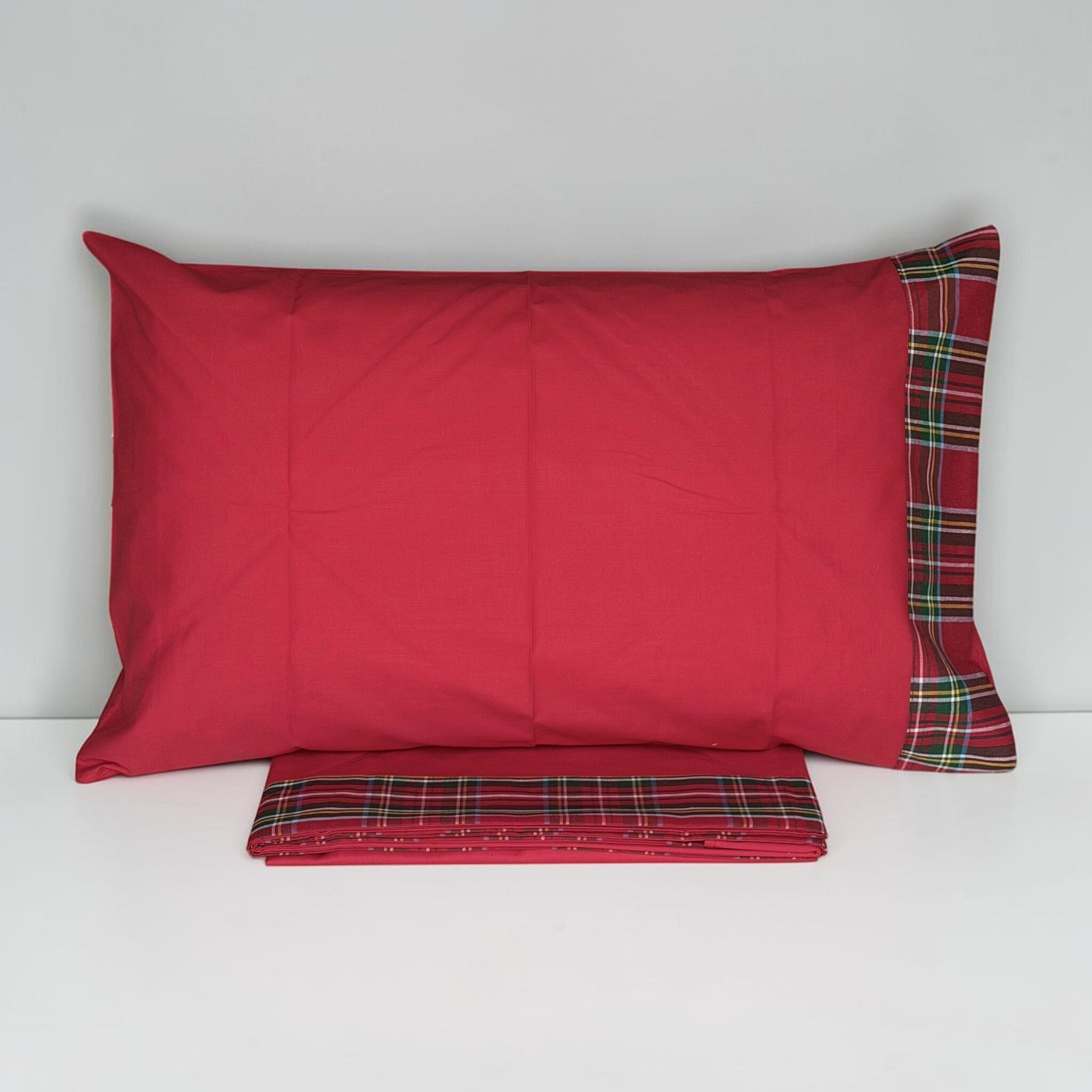 Federa rossa Carezze Vanessa con balza scozzese su un solo lato, sopra il lenzuolo ripiegato con bordo tartan.
