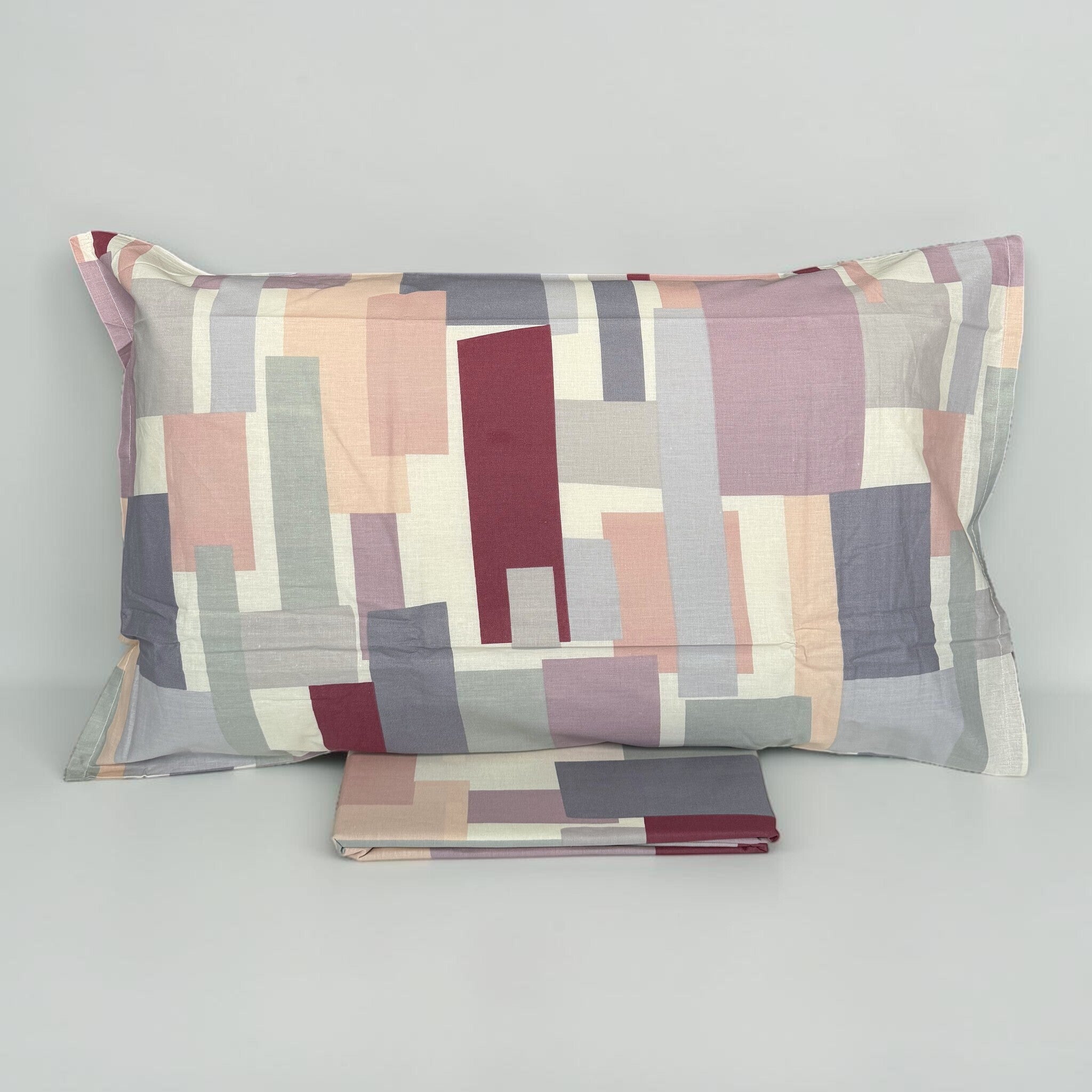 Federa Cogal 2605 Malva con rettangoli rosa, grigi e bordeaux, accanto al tessuto coordinato ripiegato.
