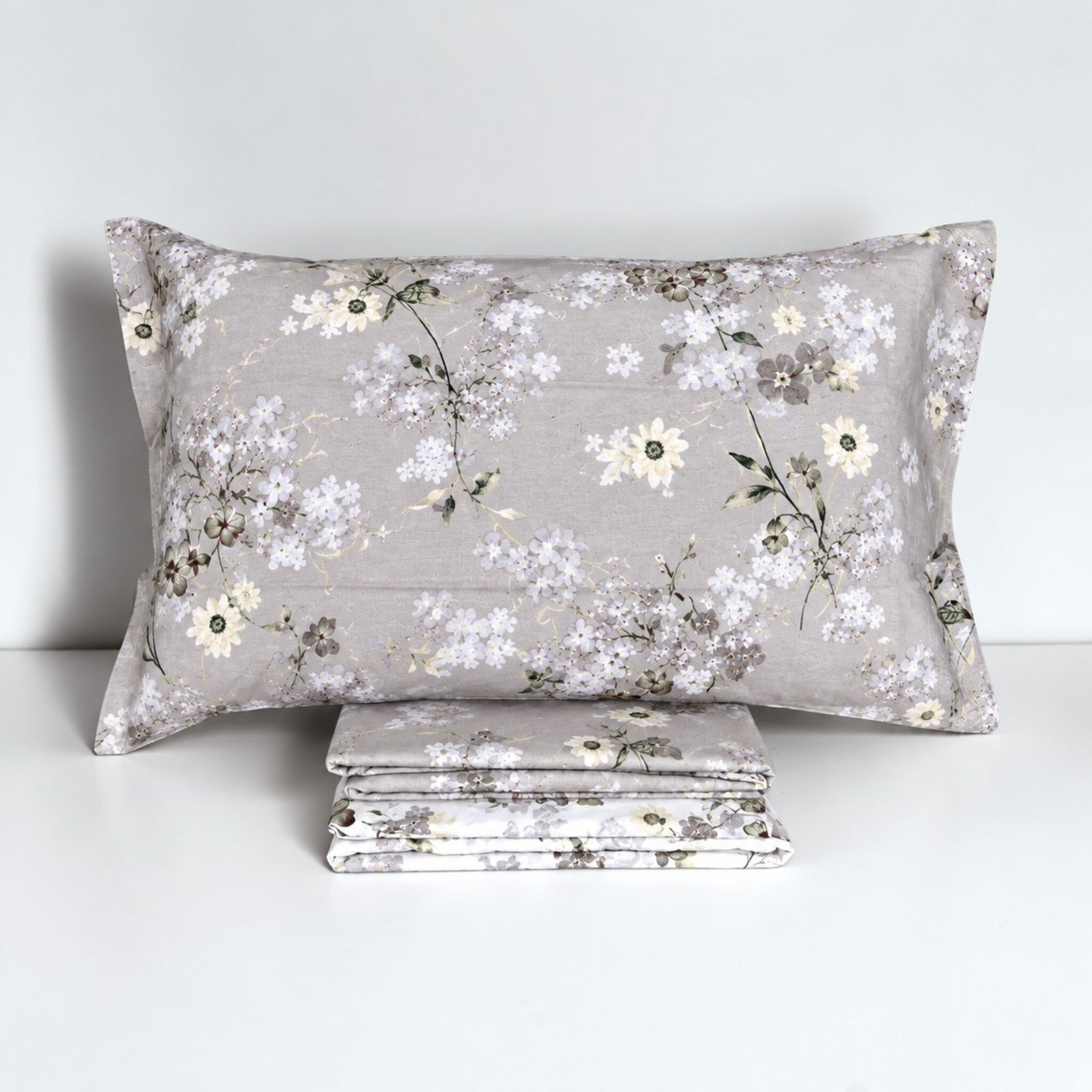 Federa Cogal 2620 Silver Grey con piccoli bouquet e foglie, accanto alle lenzuola coordinate ripiegate.