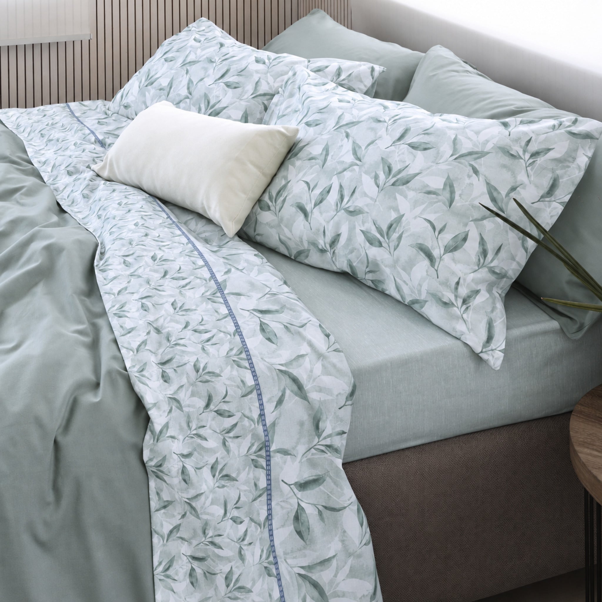 Letto matrimoniale con lenzuola Cogal 2656 Verde, federe a foglie e risvolto con motivo botanico più piccolo.