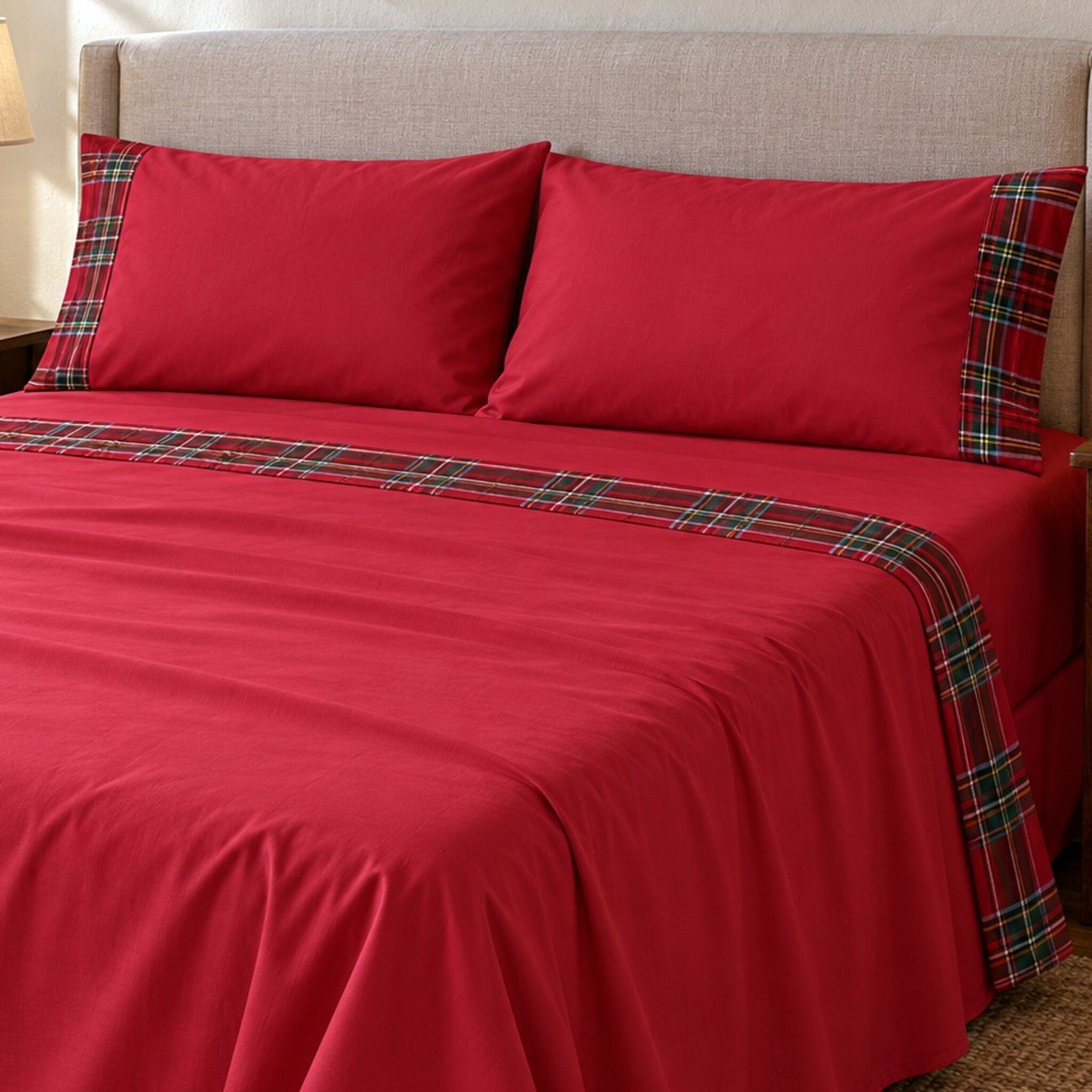 Letto matrimoniale con lenzuola Carezze Vanessa rosse, risvolto con fascia tartan e federe coordinate.
