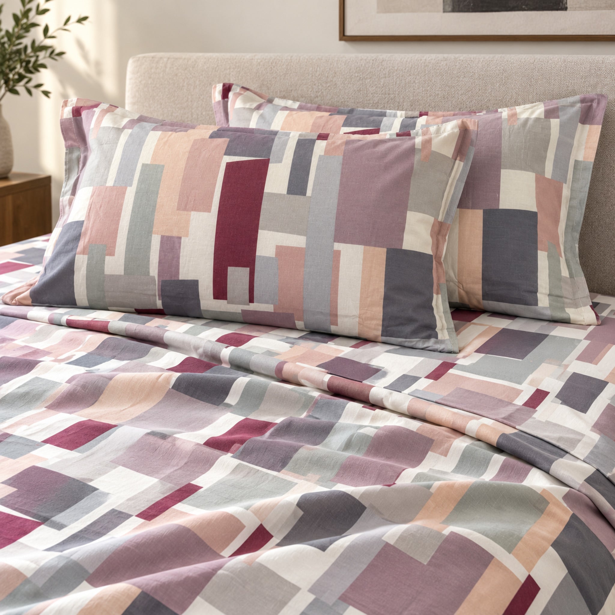 Lenzuola matrimoniali Cogal 2605 Malva sul letto, con fantasia geometrica rosa, grigia e bordeaux e federe coordinate.