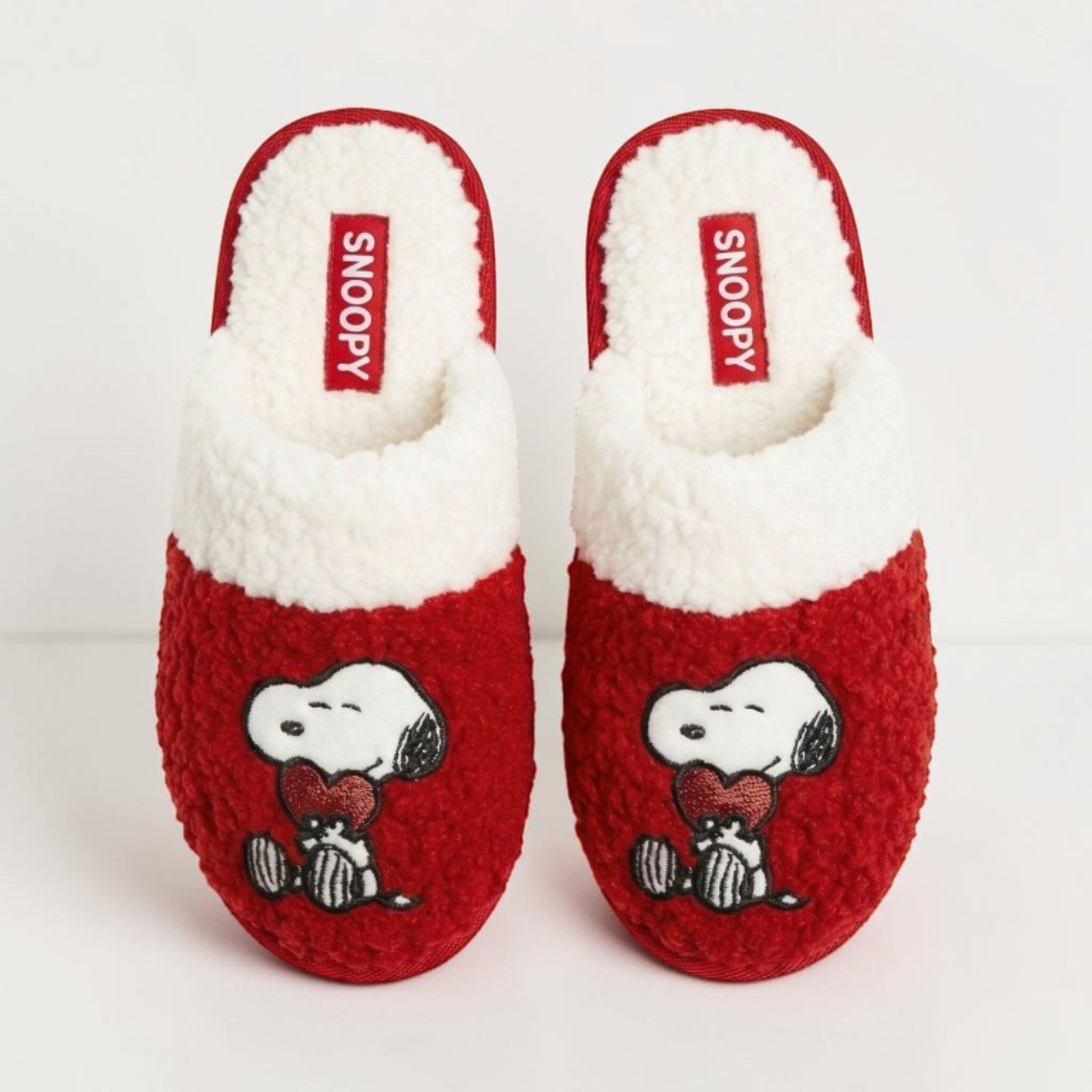 Pantofole Peanuts Love Snoopy viste dall’alto, rosse con interno bianco, etichetta Snoopy e ricamo del personaggio con cuore.