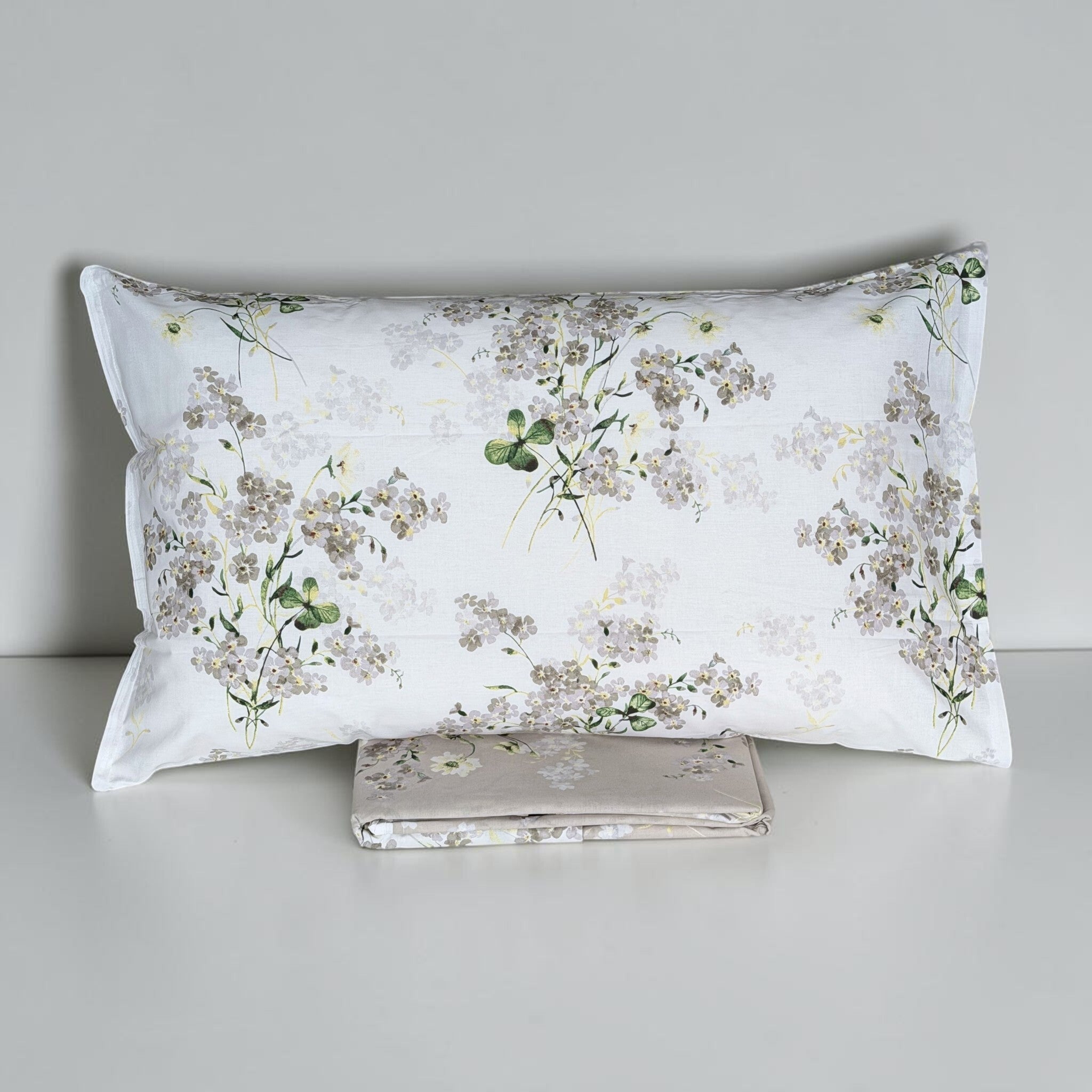 Federa Cogal 2620 sul lato bianco con piccoli fiori e foglie verdi, sopra il sacco Silver Grey ripiegato.