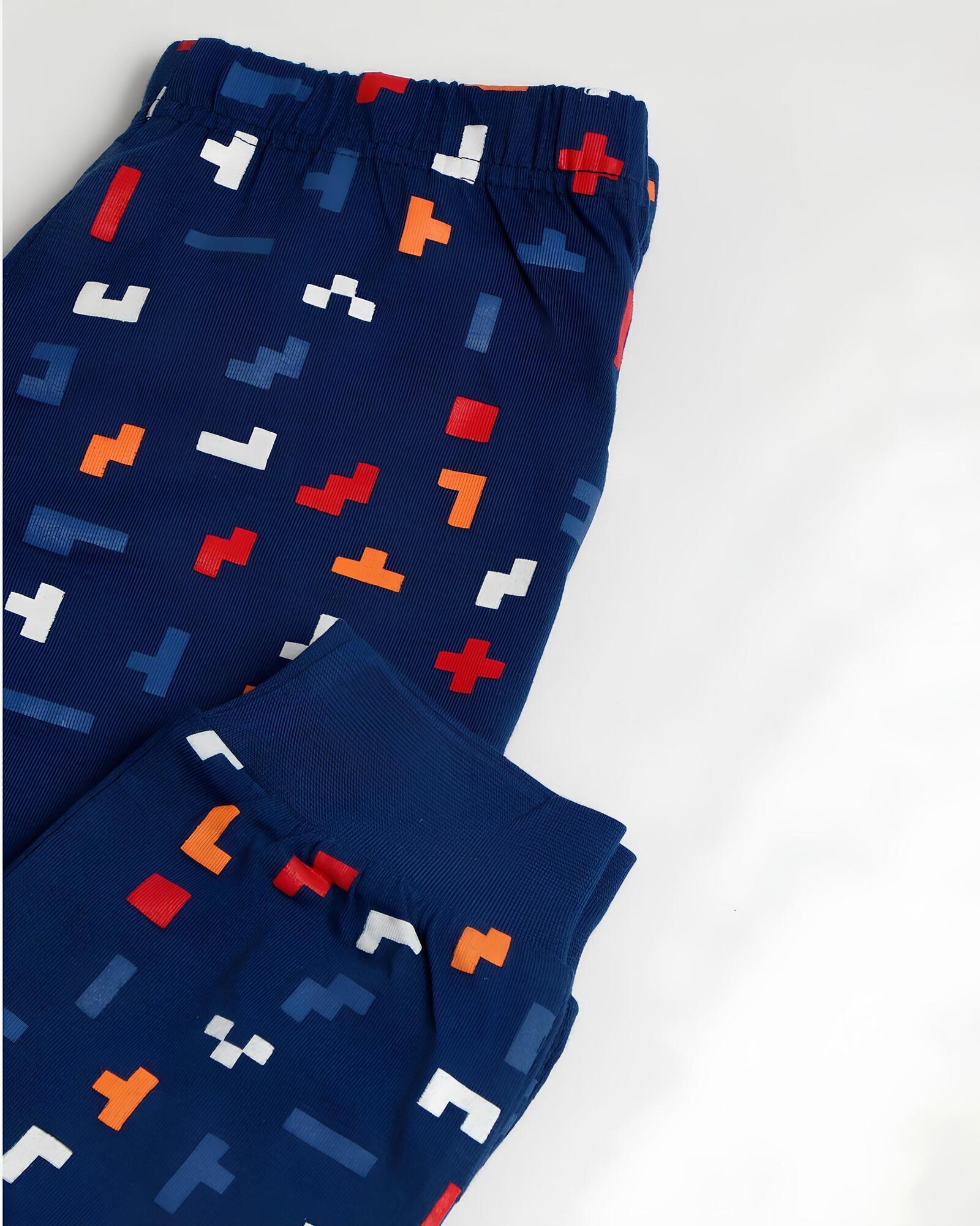 Dettaglio dei pantaloni blu con vita elasticizzata, polsini e fantasia geometrica rossa, arancione, bianca e azzurra