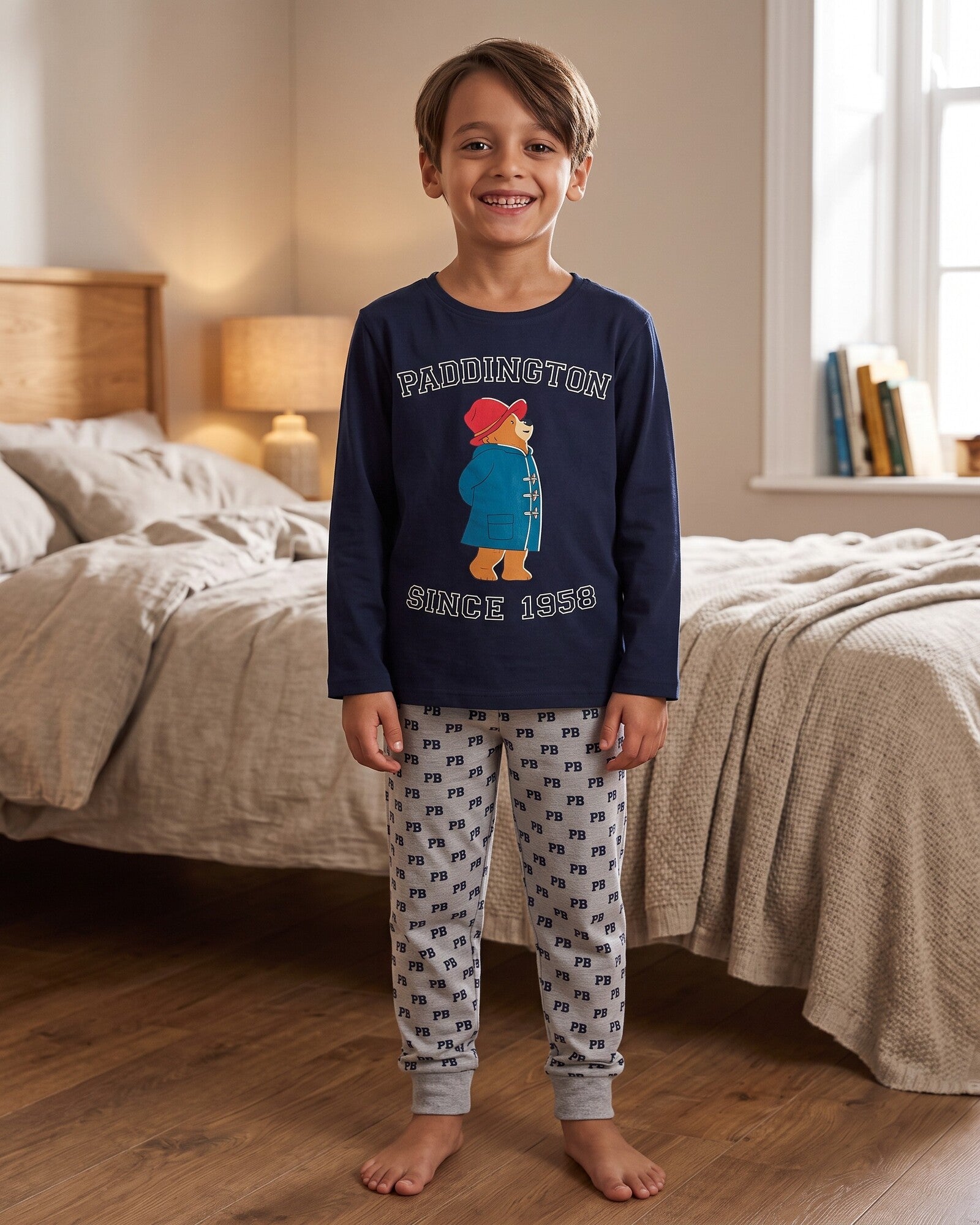 Bambino con pigiama Paddington, maglia blu navy Since 1958 e pantaloni grigio mélange con motivo PB e polsini