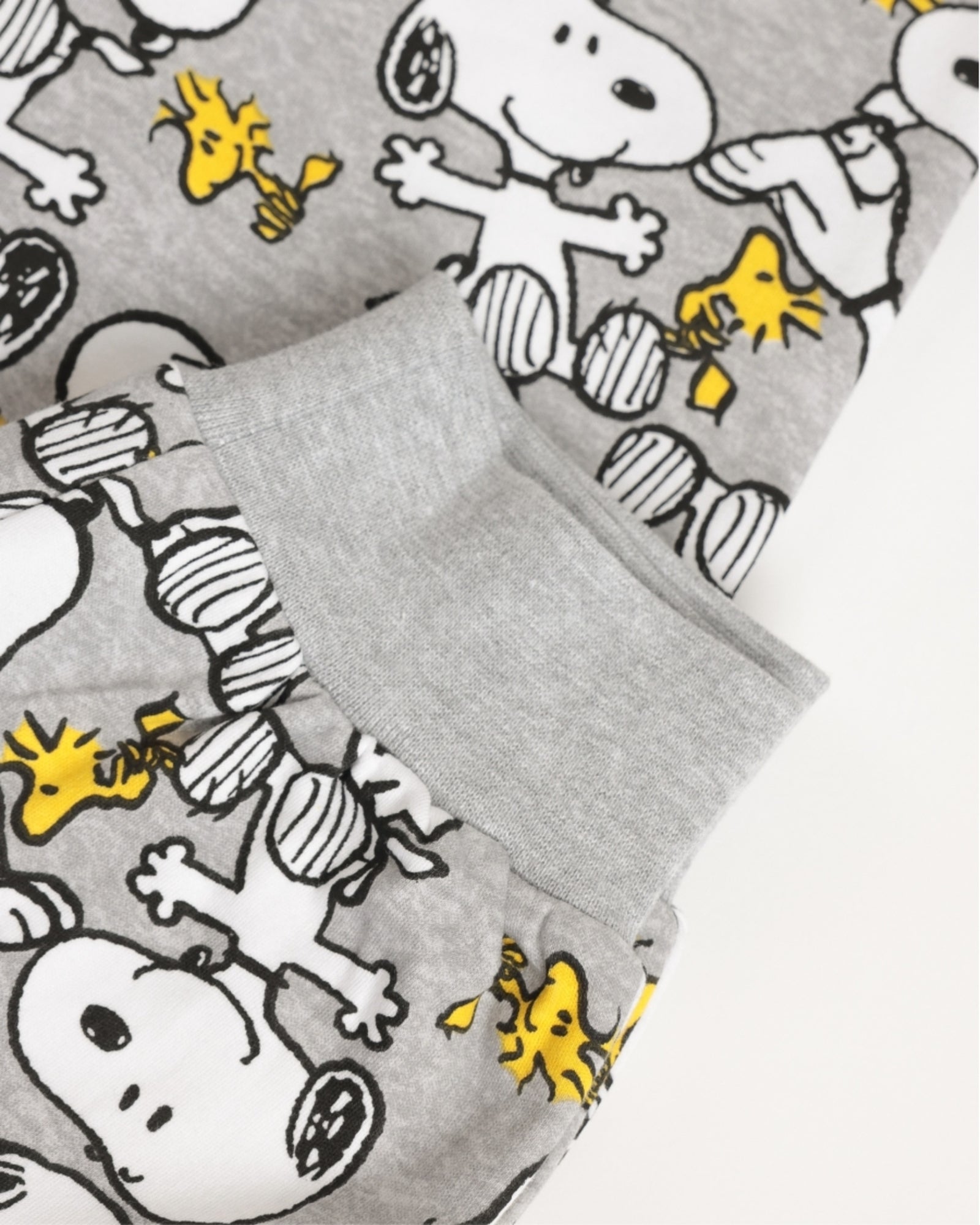 Dettaglio dei pantaloni del pigiama bambino con polsini grigi alle caviglie e fantasia Snoopy e Woodstock