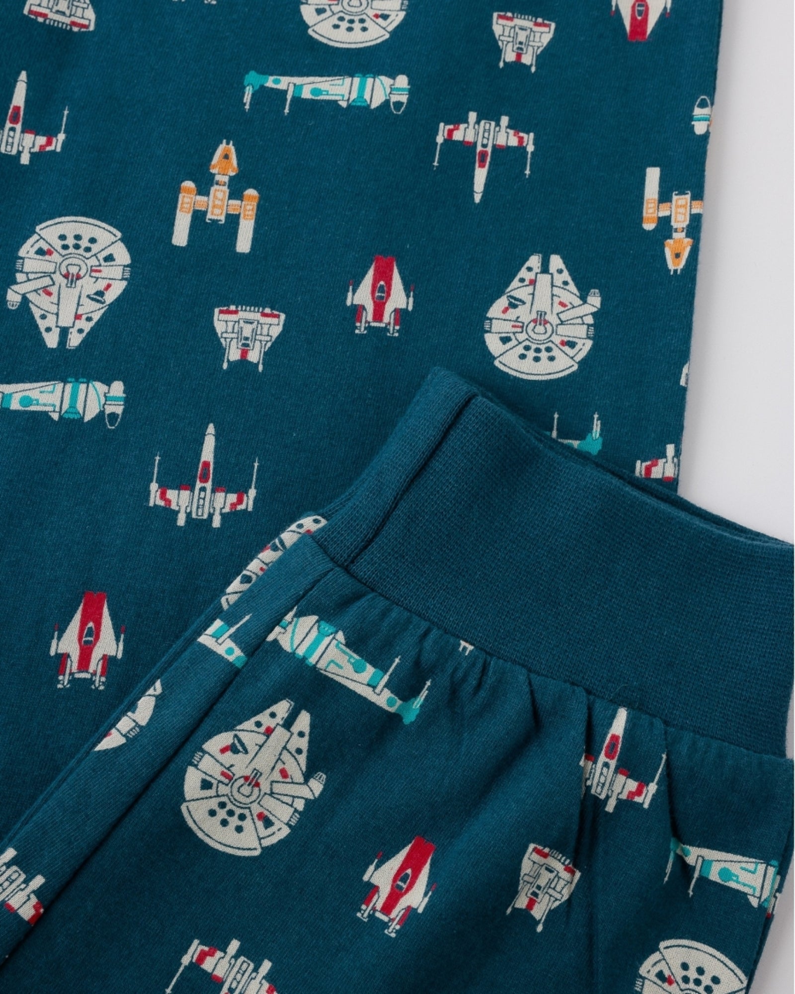 Dettaglio dei pantaloni blu oceano con fantasia di astronavi Star Wars e polsino al fondo gamba