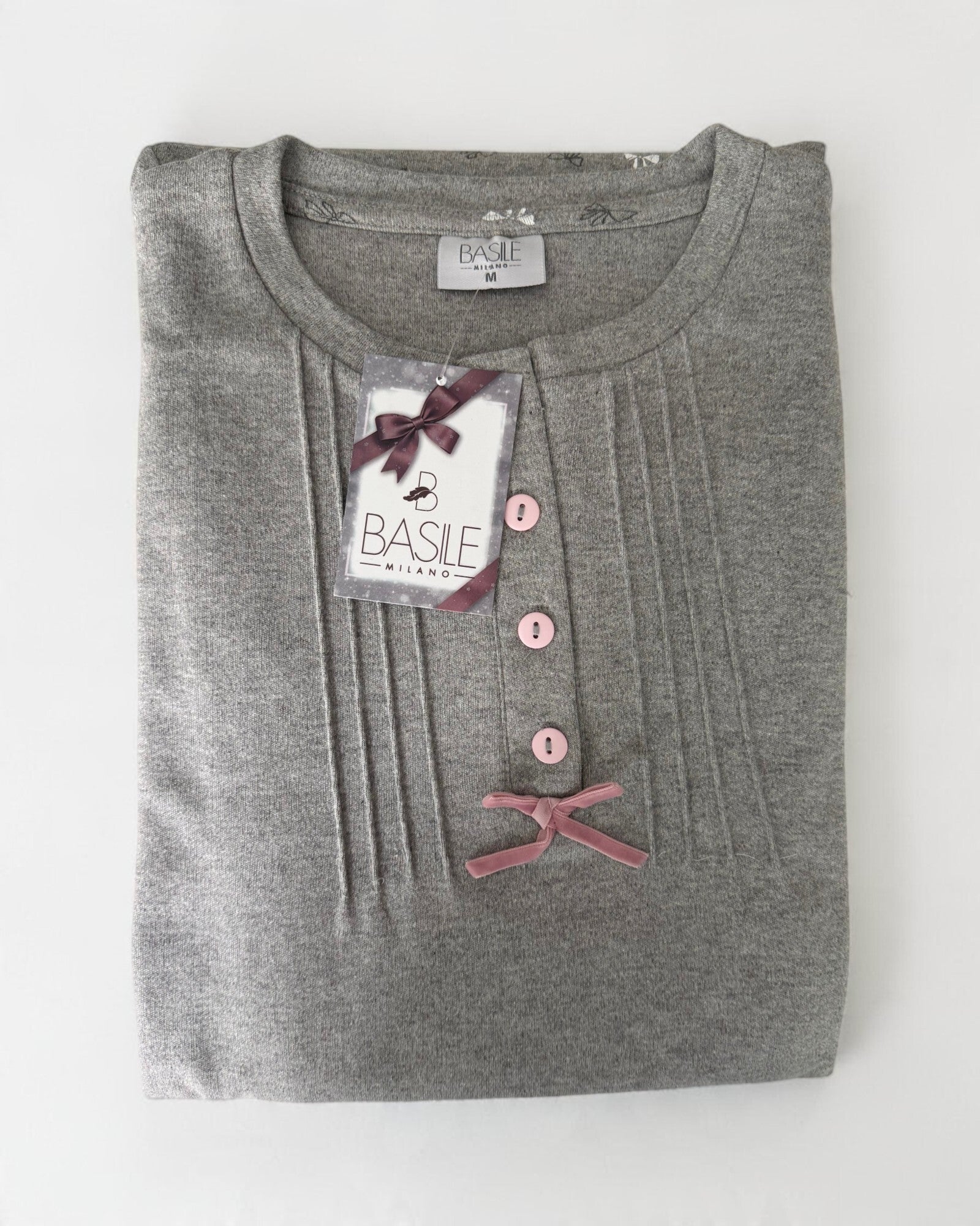Maglia grigia del pigiama Basile Milano 3130 piegata, con bottoni rosa, fiocco in velluto e cartellino del marchio