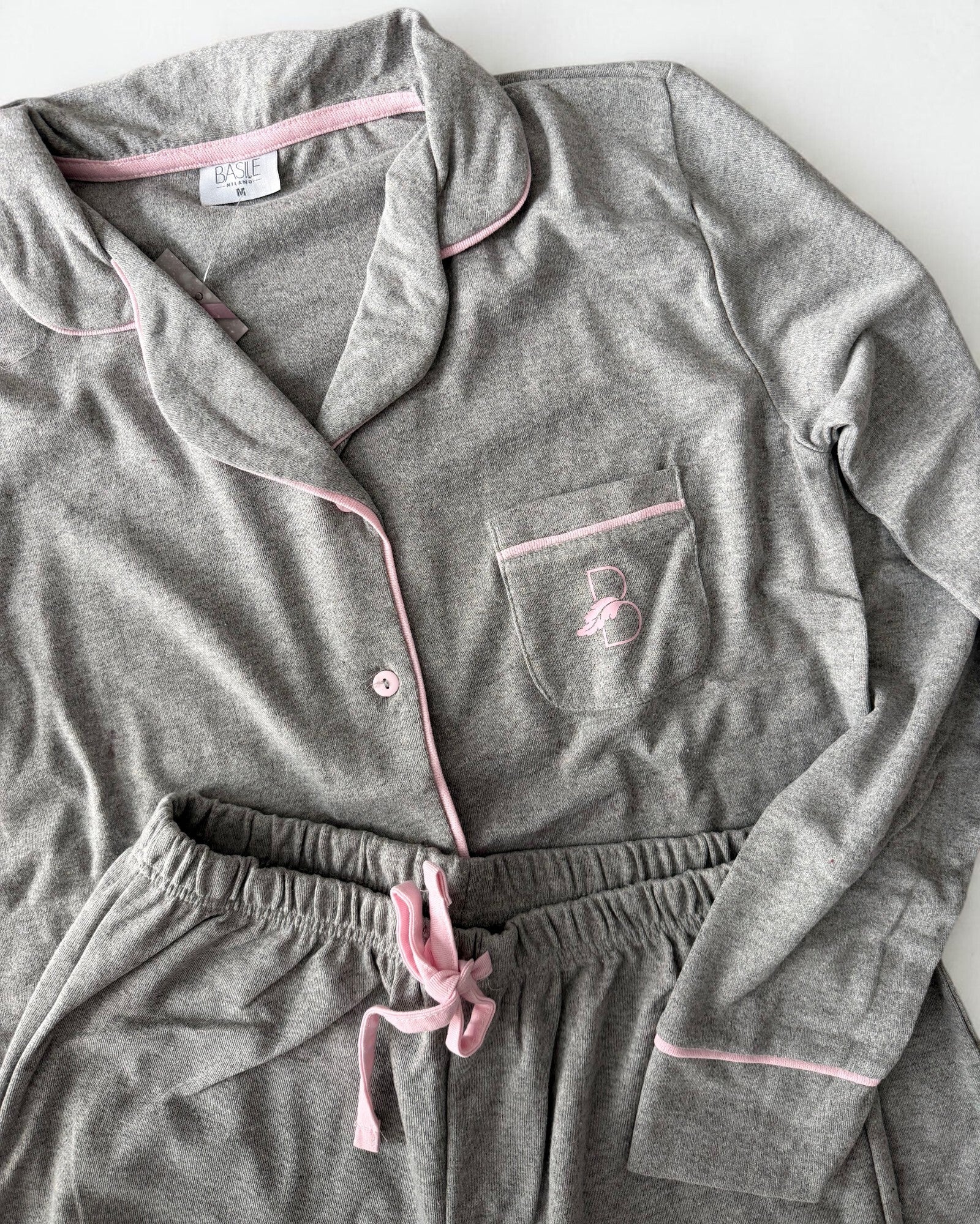 Dettaglio del pigiama grigio Basile Milano 4130 con taschino logato, piping rosa ed elastico in vita con laccetto