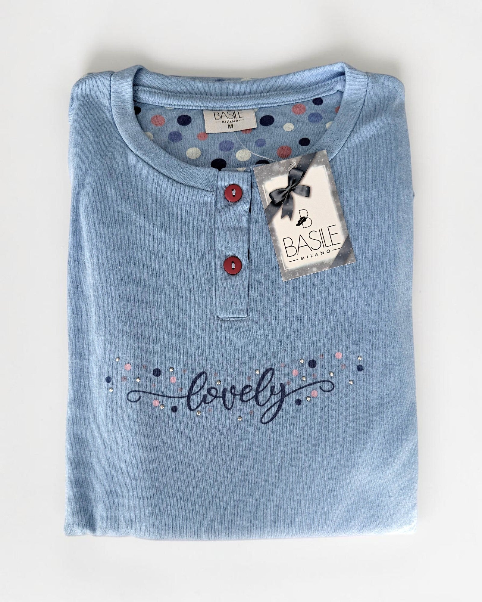 Maglia celeste del pigiama Basile Milano 4030 piegata, con due bottoni a contrasto e stampa Lovely con dettagli luminosi.
