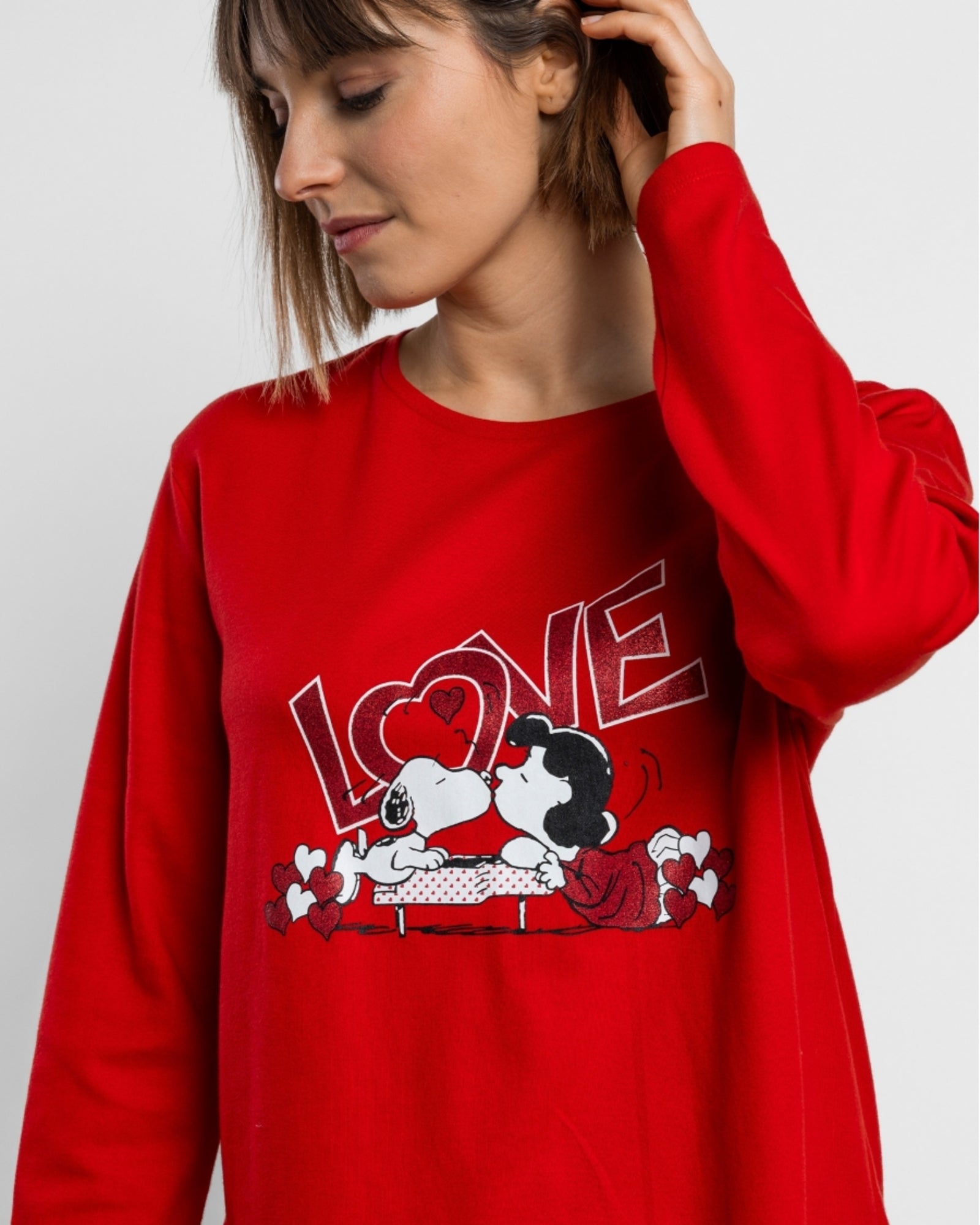 Dettaglio della maglia rossa Peanuts con Snoopy, Lucy, cuori e scritta LOVE con dettagli glitter