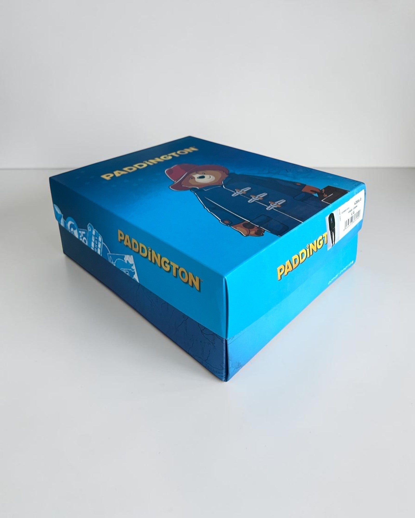 Scatola regalo blu con logo Paddington e illustrazione dell’orsetto con cappello rosso e montgomery blu