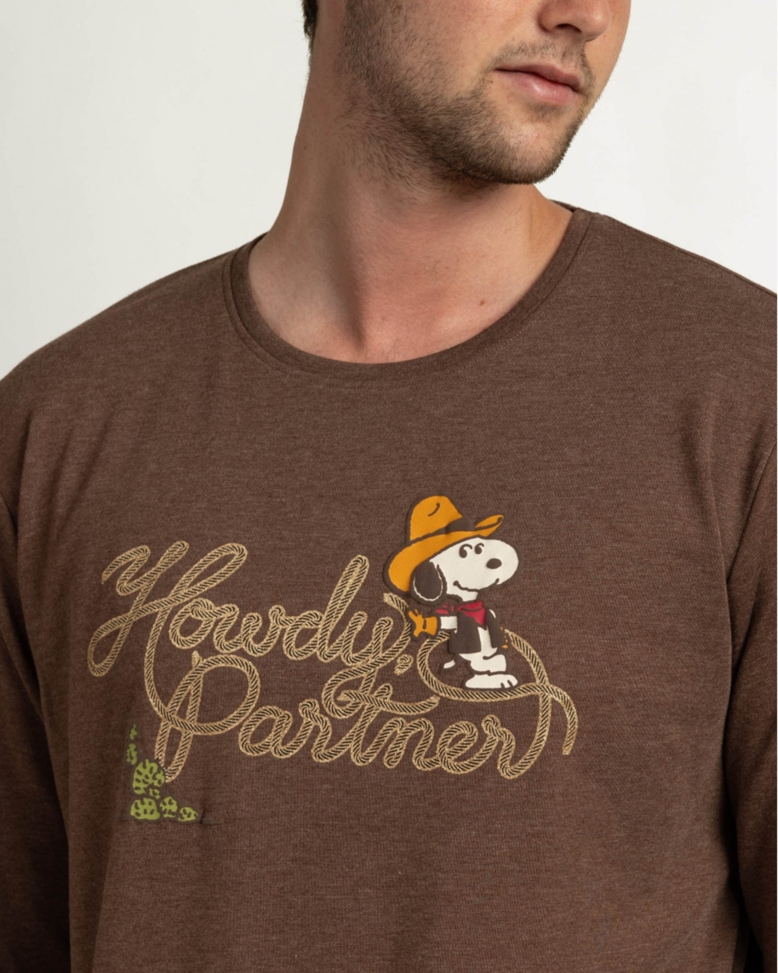 Dettaglio della maglia marrone mélange con Snoopy cowboy, scritta Howdy Partner e dettagli metallizzati