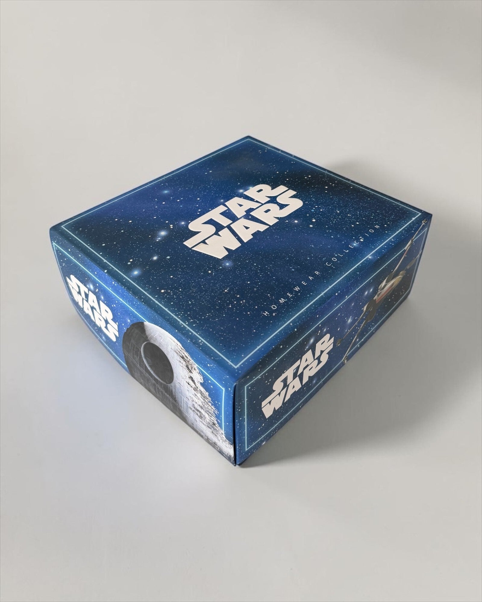 Scatola blu del pigiama Star Wars 64490, con logo bianco, fondo stellato e immagini della Morte Nera e delle astronavi.
