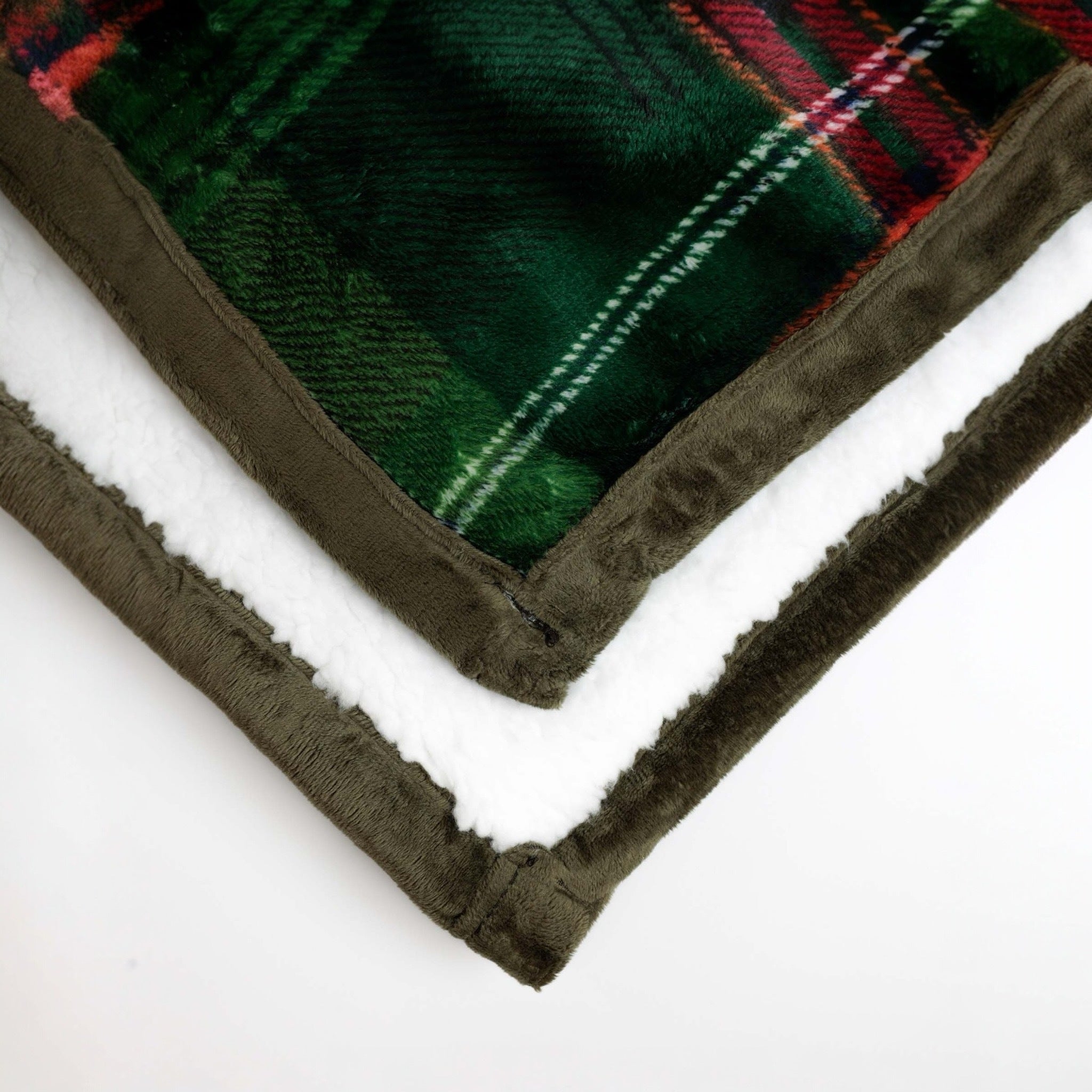 Dettaglio degli angoli del plaid Admas con bordo verde oliva, lato tartan verde e retro soffice in sherpa bianca.