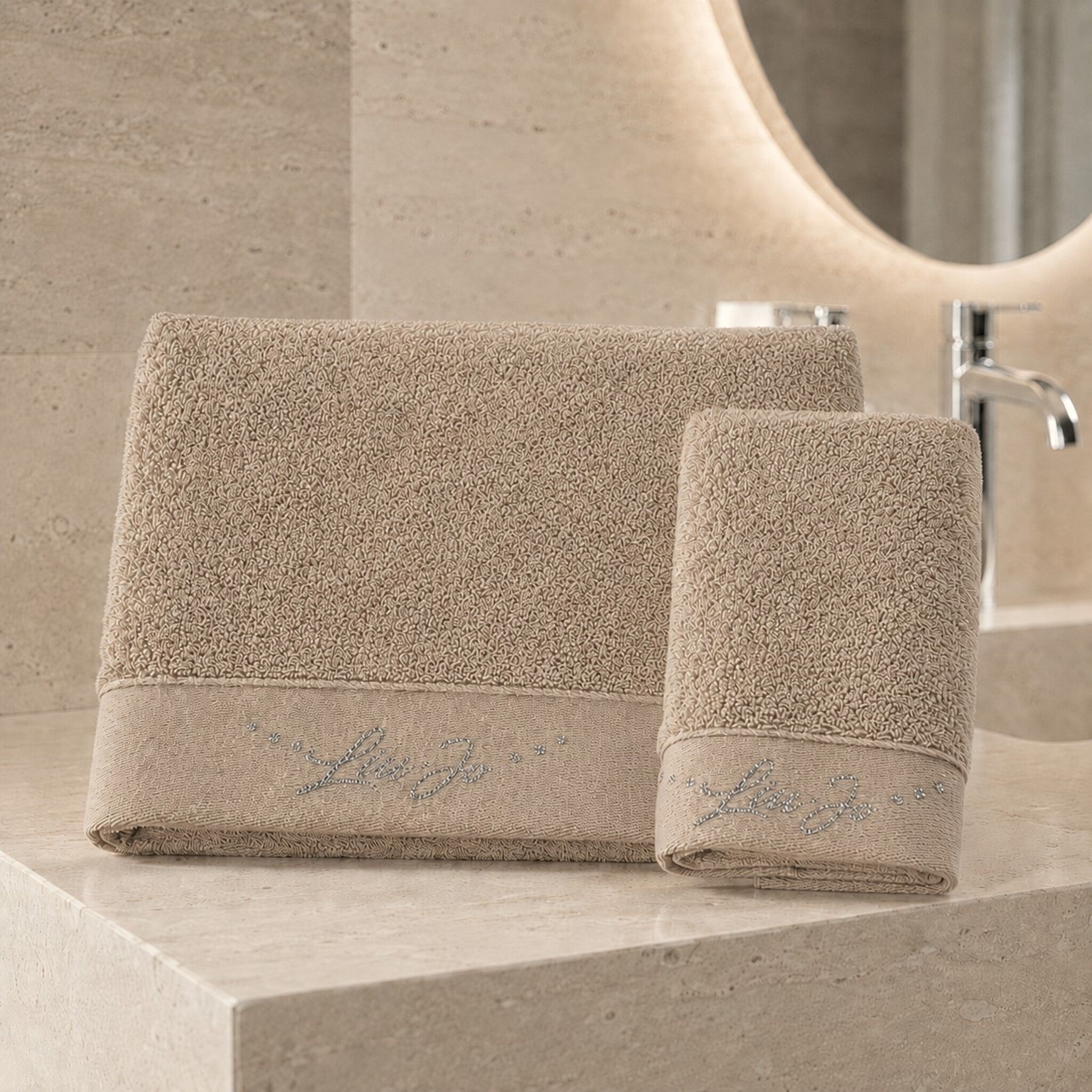 Set asciugamani 1+1 Liu Jo Happy colore sabbia con telo viso e ospite ambientati in un bagno elegante
