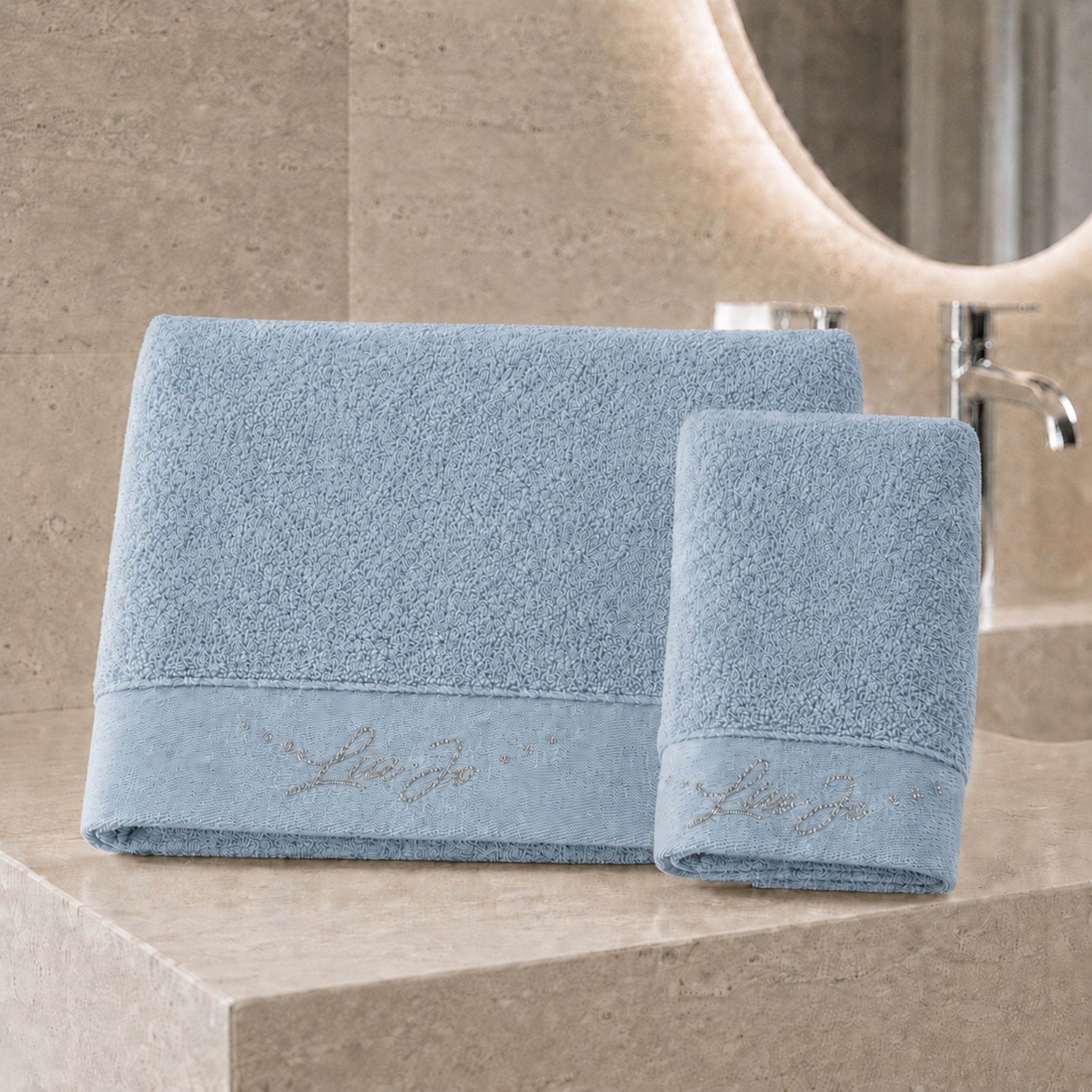 Set asciugamani 1+1 Liu Jo Happy colore zucchero con telo viso e ospite ambientati in un bagno elegante