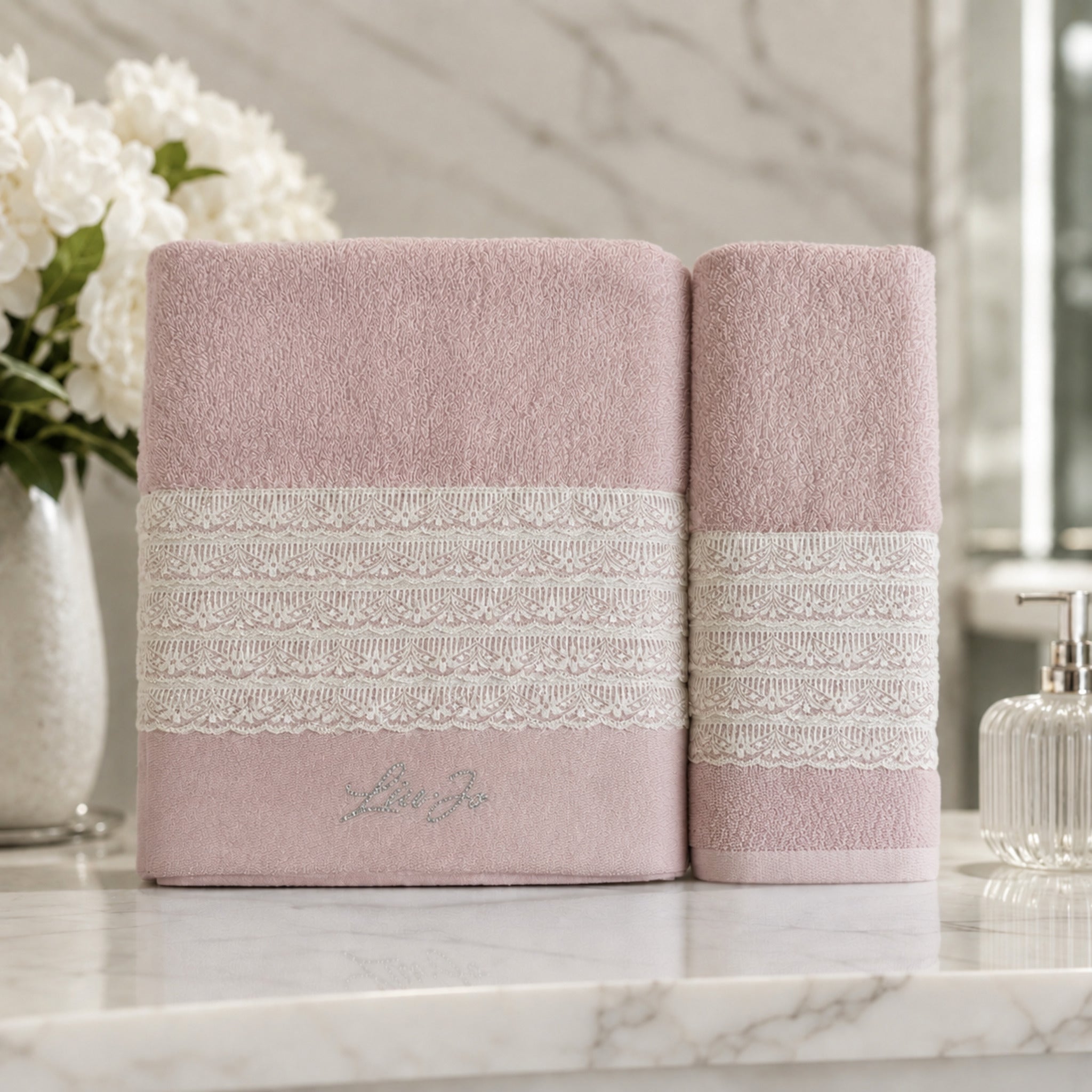 Set asciugamani 1+1 Liu Jo Paradiso Rosy con telo viso e ospite ambientati in un bagno elegante