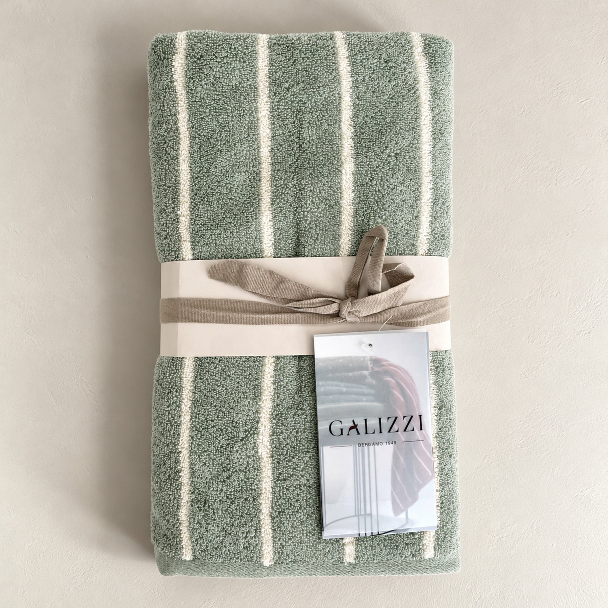 Set asciugamani Saint Louis Smoke Green presentato con fascetta chiara, nastro annodato e cartellino del marchio.
