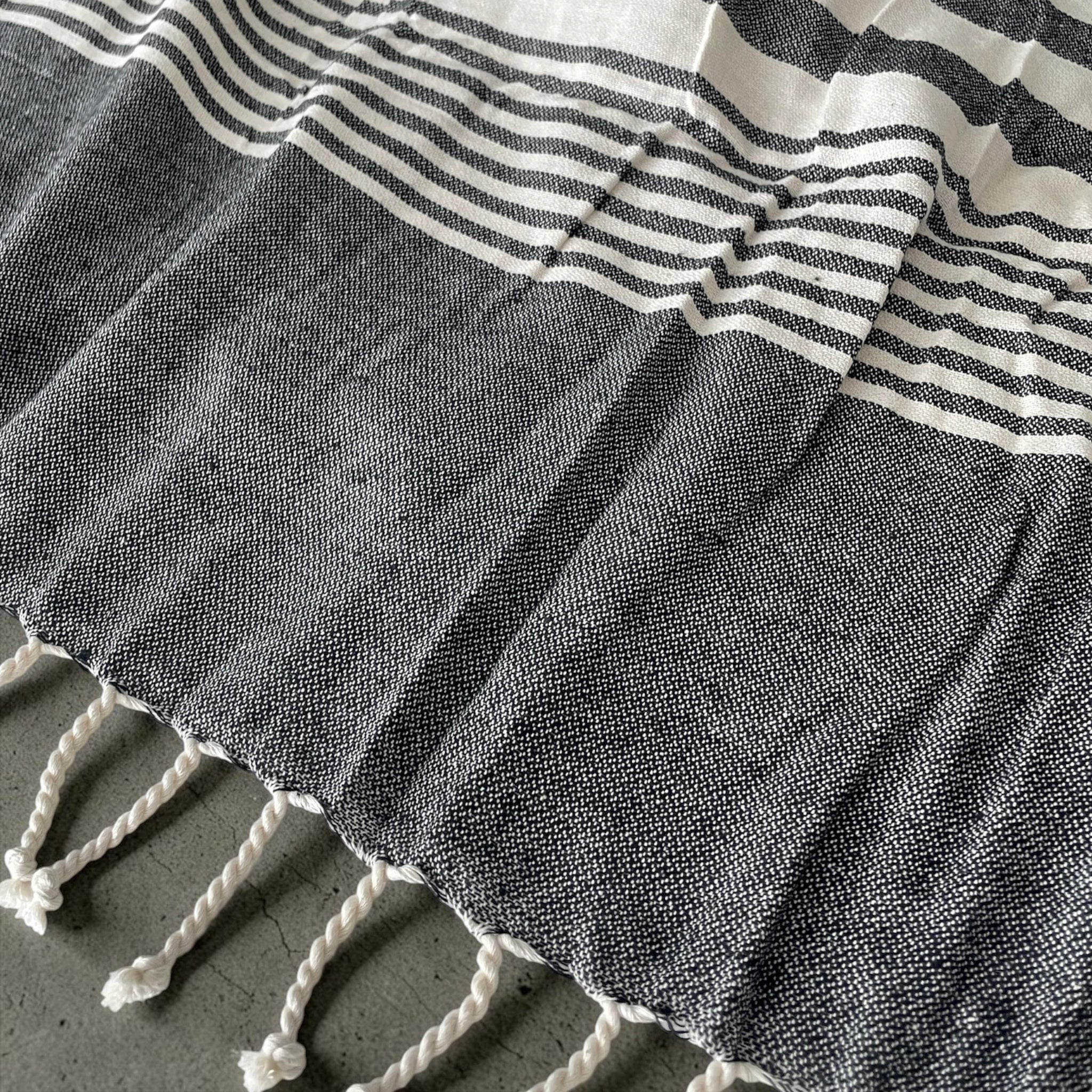 Dettaglio tessuto 100% cotone del telo mare fouta Cogal Guadalupa con fantasia a righe e frange antracite