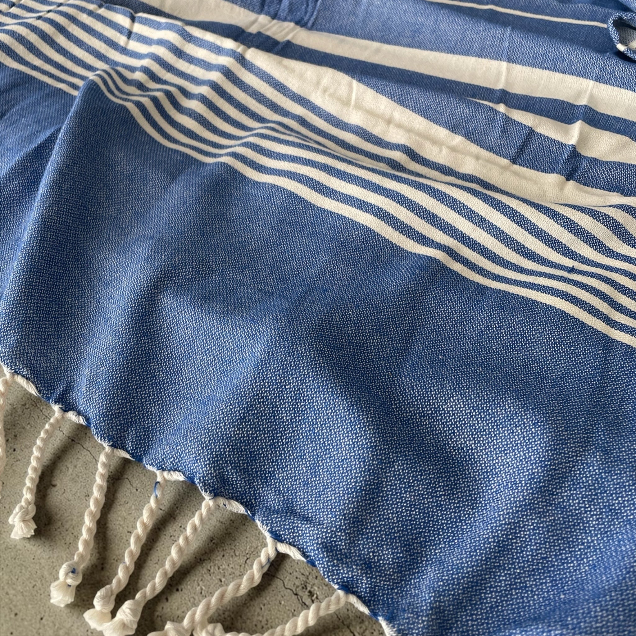 Dettaglio tessuto 100% cotone del telo mare fouta Cogal Guadalupa con fantasia a righe e frange blu