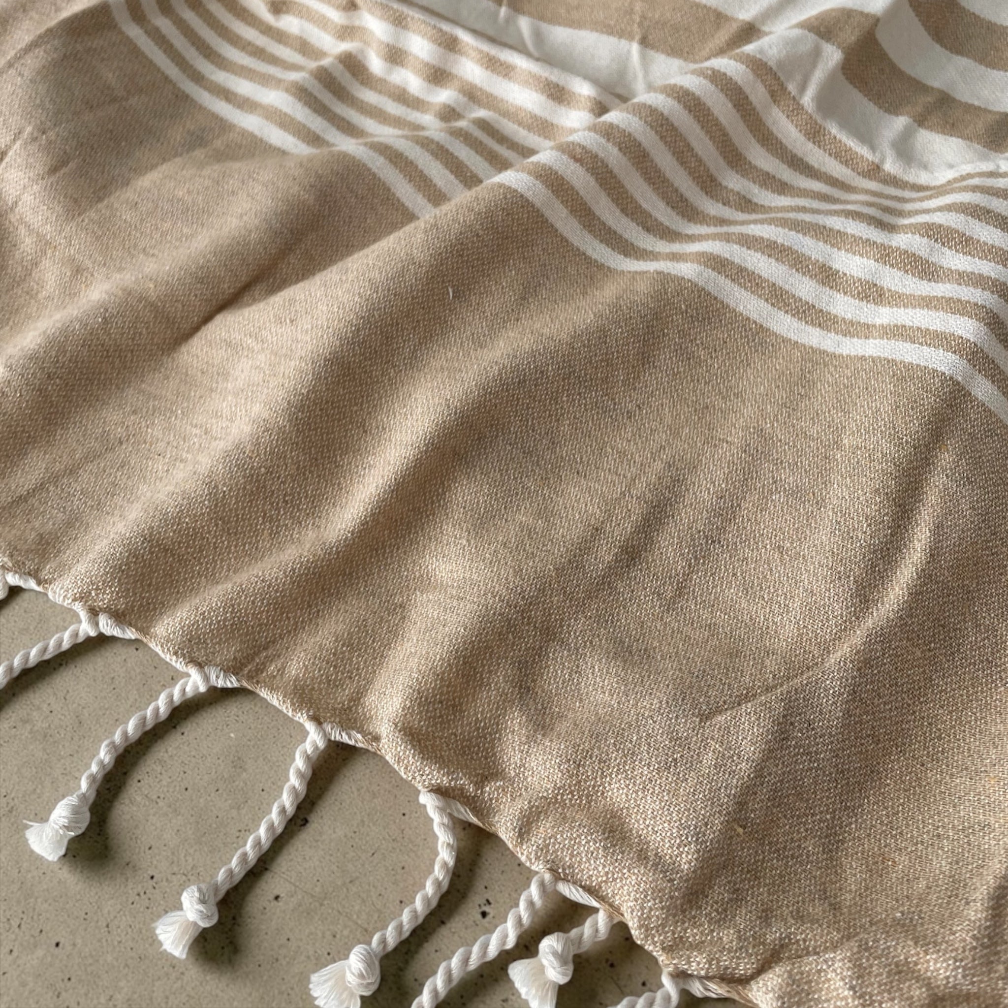 Dettaglio tessuto 100% cotone del telo mare fouta Cogal Guadalupa con fantasia a righe e frange sabbia