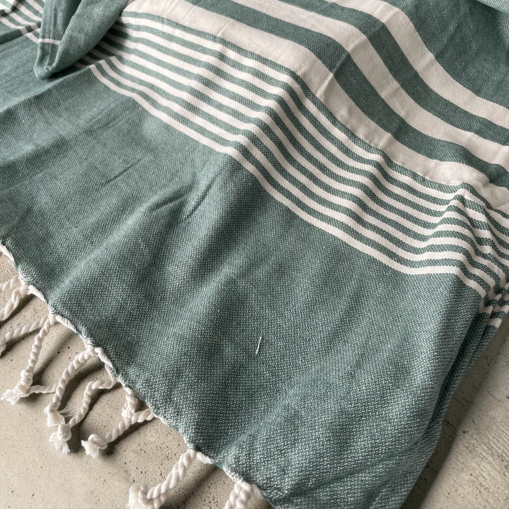 Dettaglio tessuto 100% cotone del telo mare fouta Cogal Guadalupa con fantasia a righe e frange verde