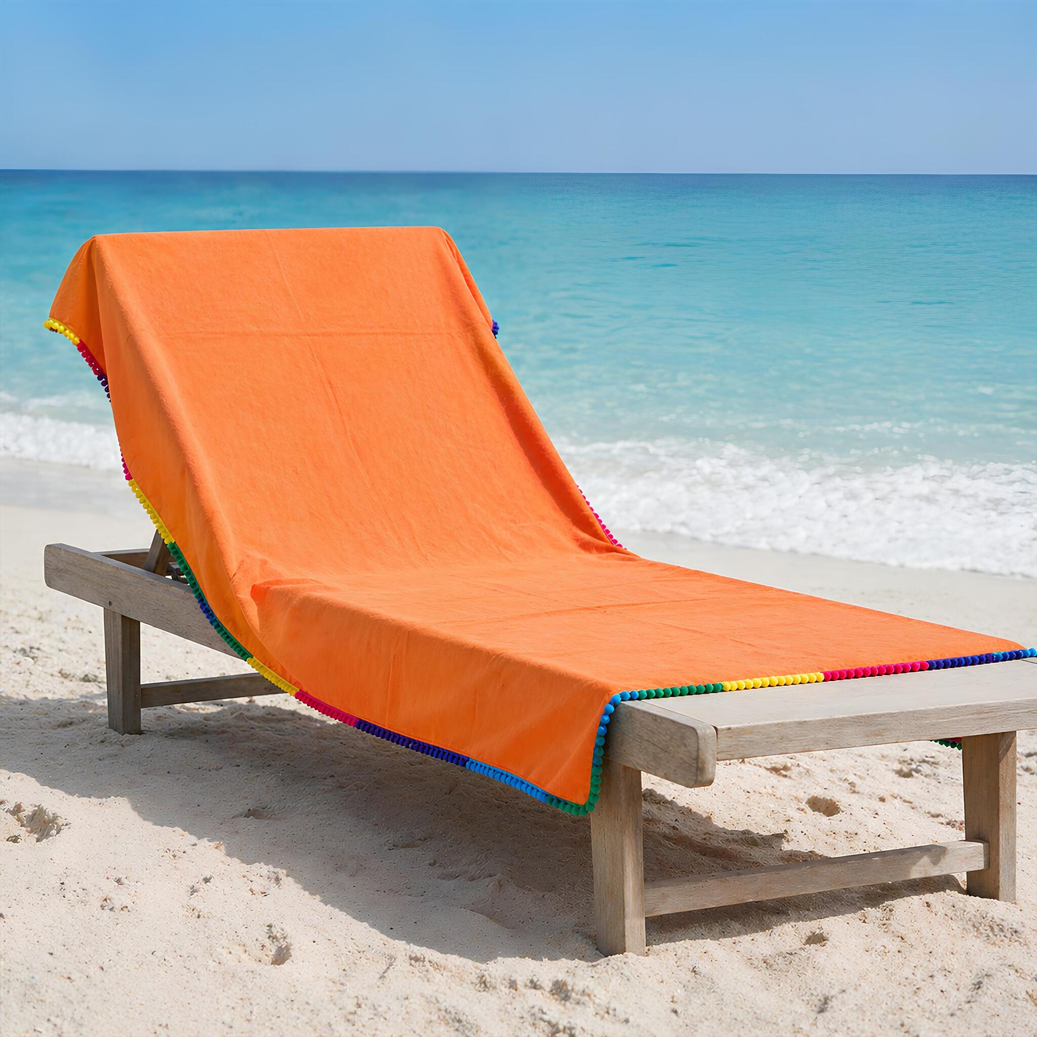 telo mare microfibra arancio con pon pon colorati su lettino spiaggia