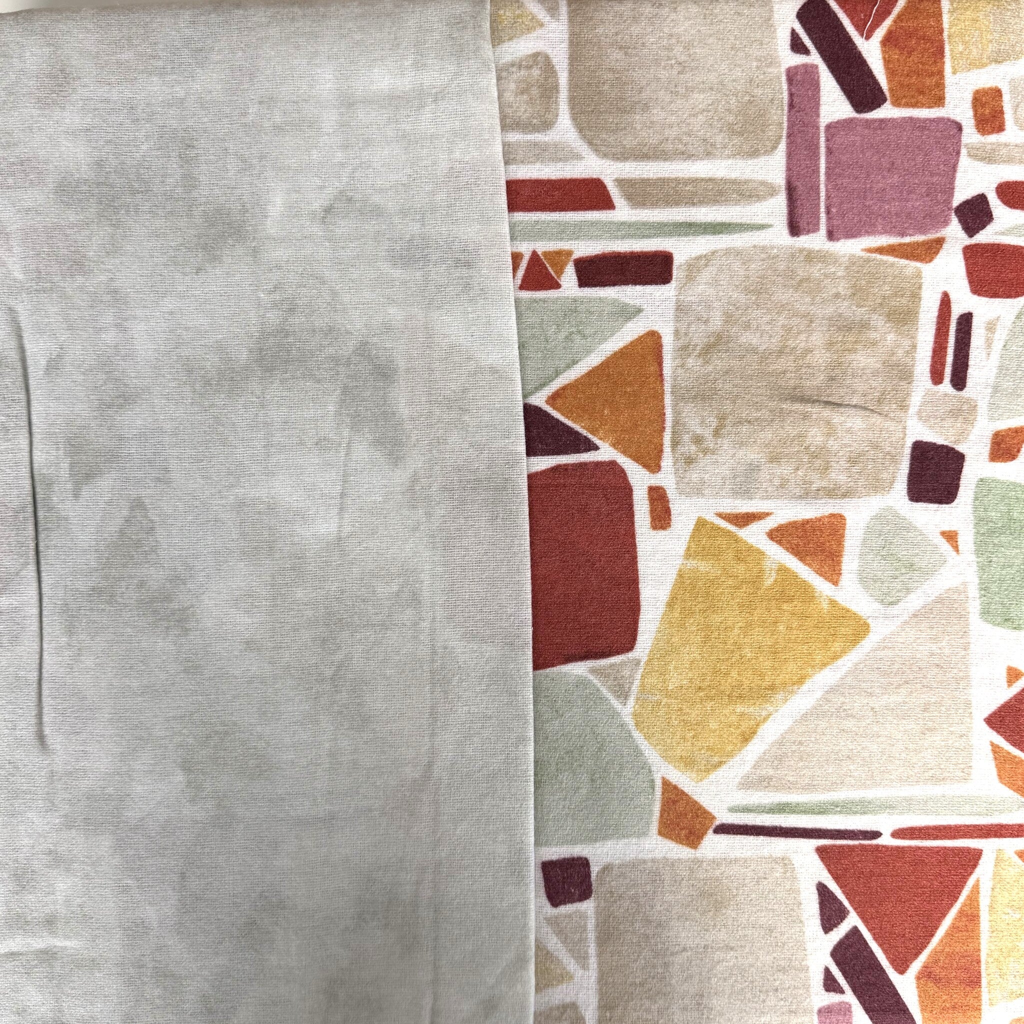 Primo piano del tessuto Cogal 2657: falso unito grigio accanto alla fantasia geometrica Multicolor con forme irregolari.