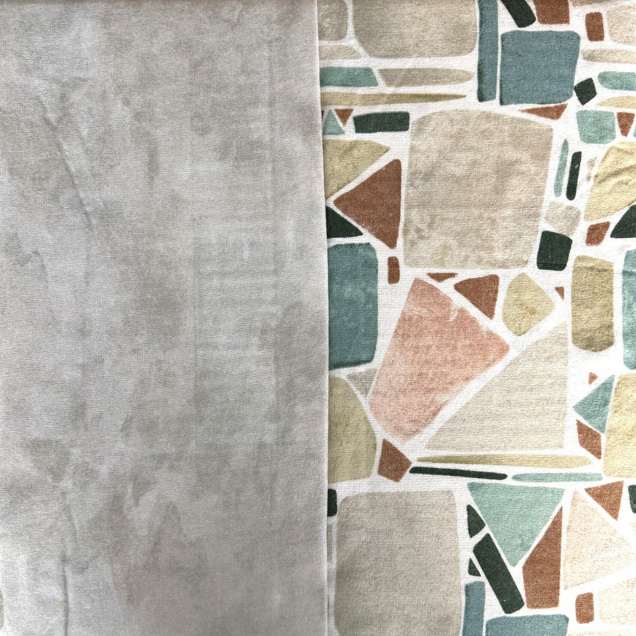 Primo piano del tessuto Cogal 2657: falso unito grigio accanto al disegno geometrico verde, beige e rosa cipria.
