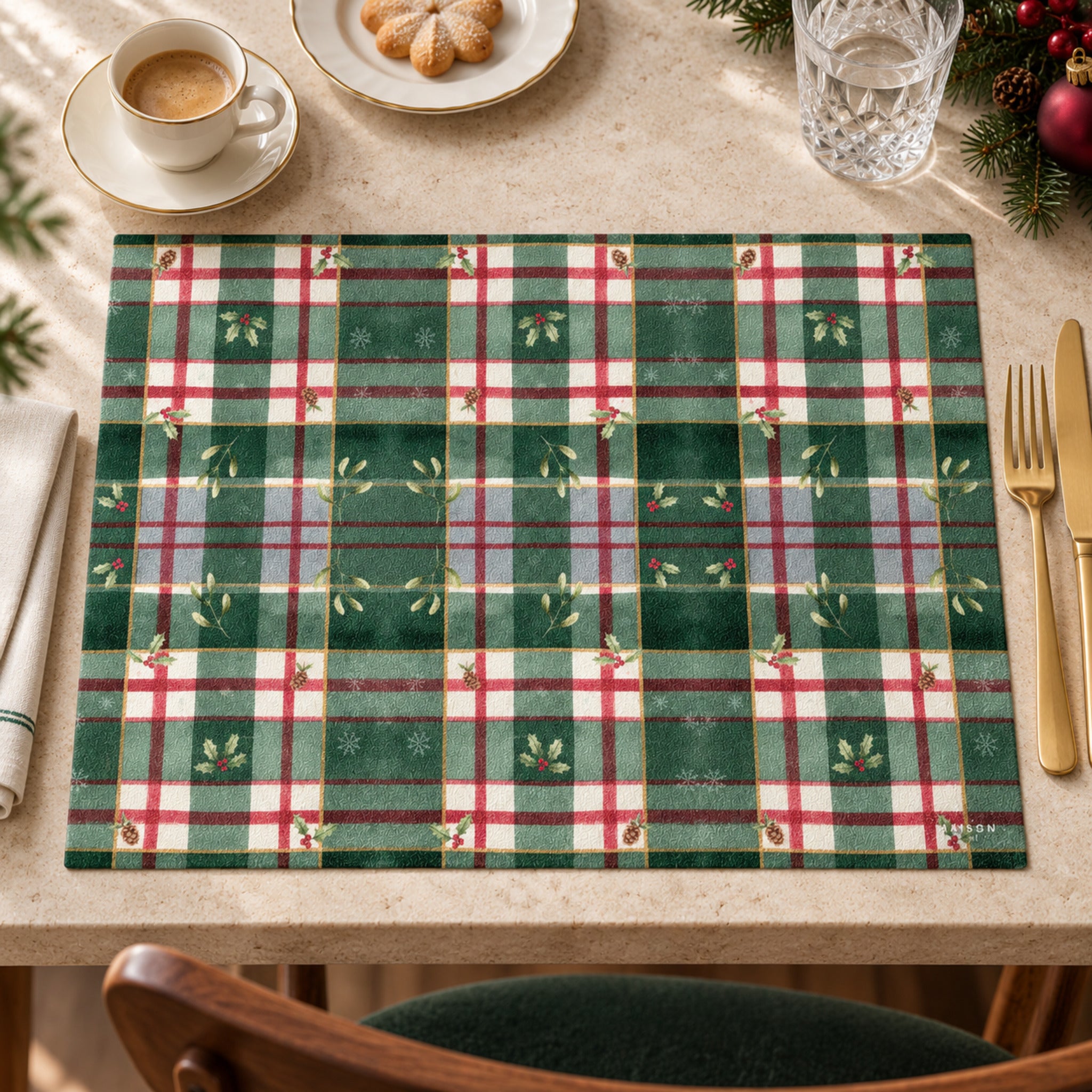 Tovaglietta natalizia Maison Sucrée a quadri tartan verdi, rossi e avorio su tavola con tazza e piattino.