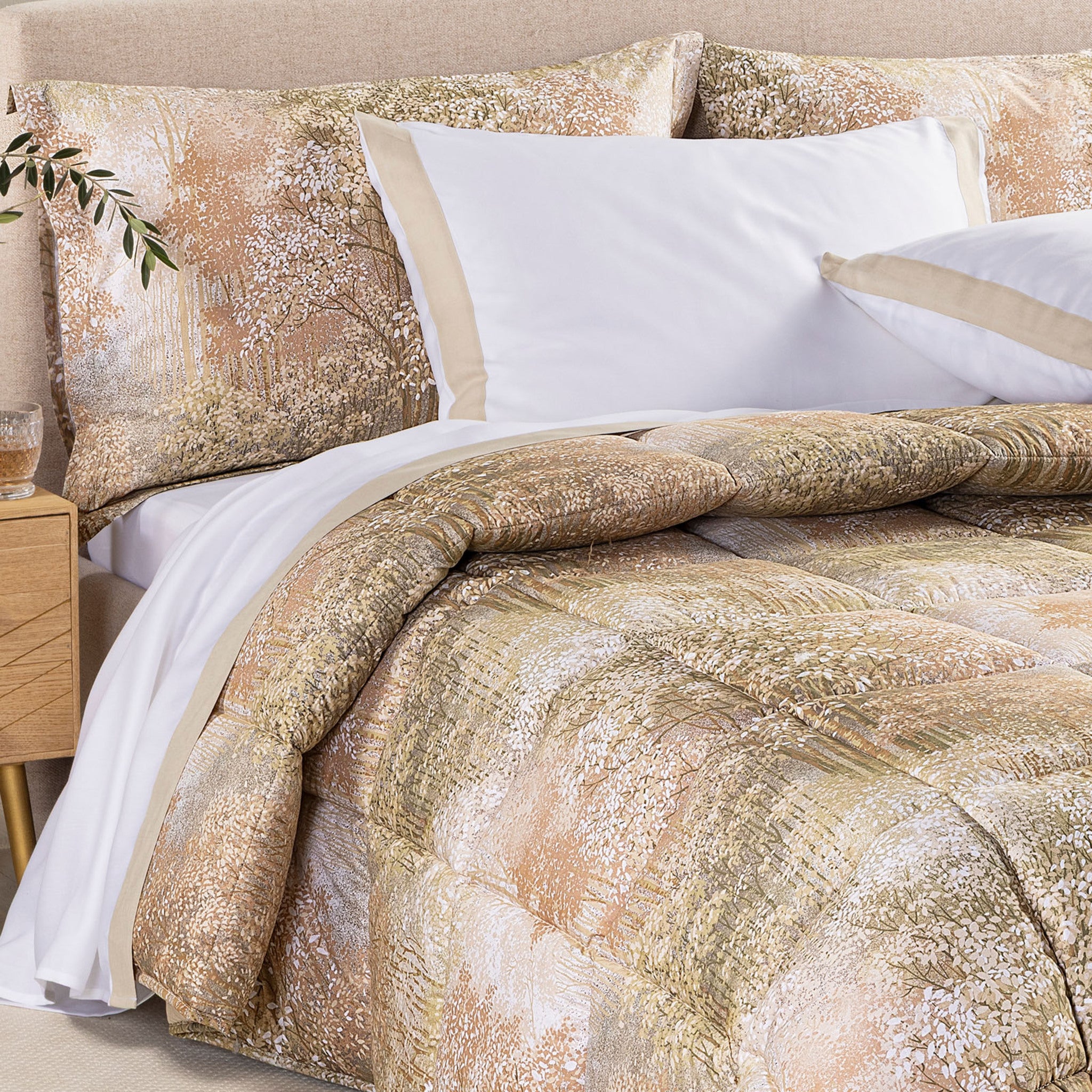 Dettaglio del risvolto della trapunta Caleffi Bosco con fantasia botanica nei toni beige, pesca e verde oliva tenue